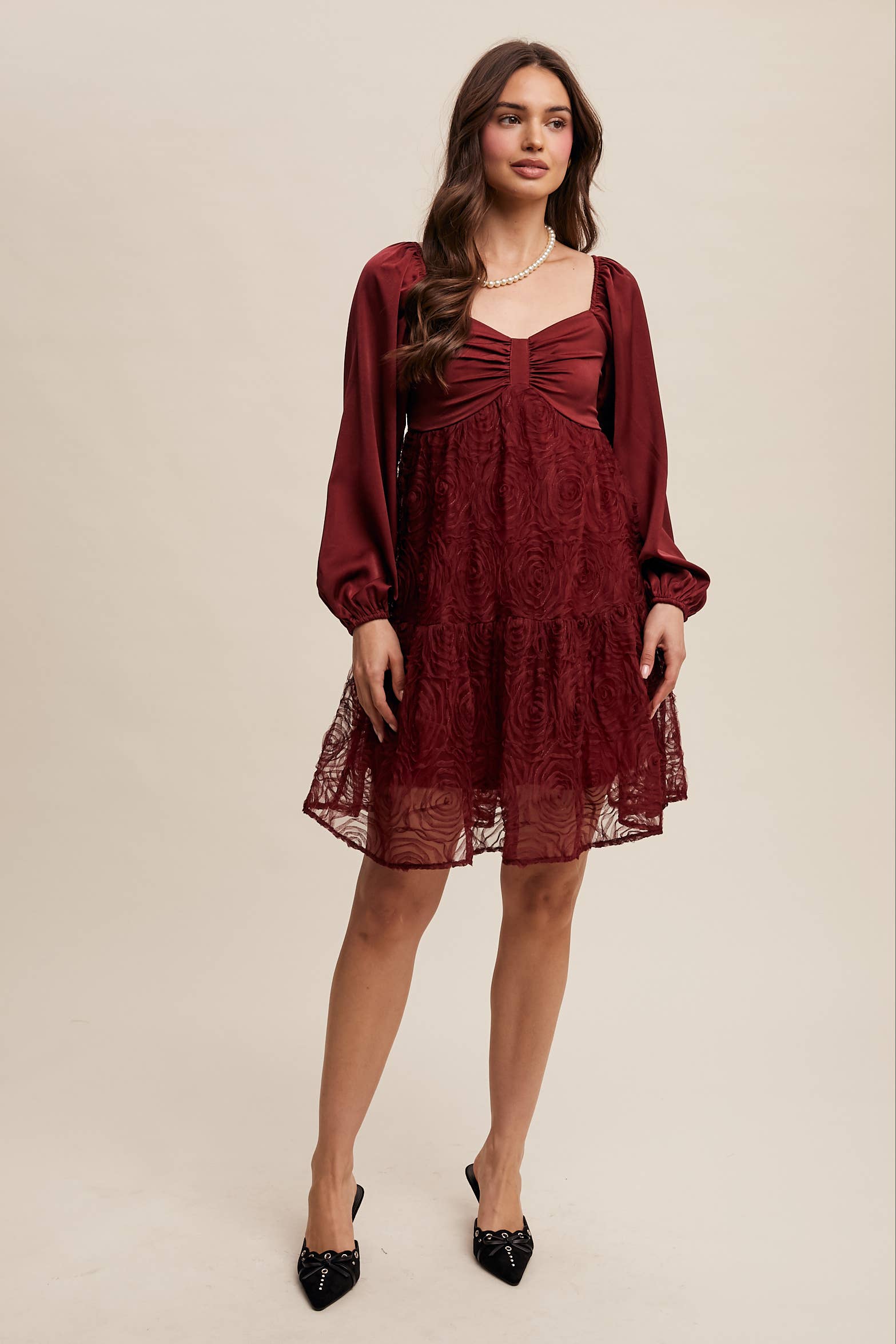 Model wearing oxblood red rosette mini dress with ruched sweetheart neckline, puff long sleeves, and tiered lace skirt — elegant and romantic look.
