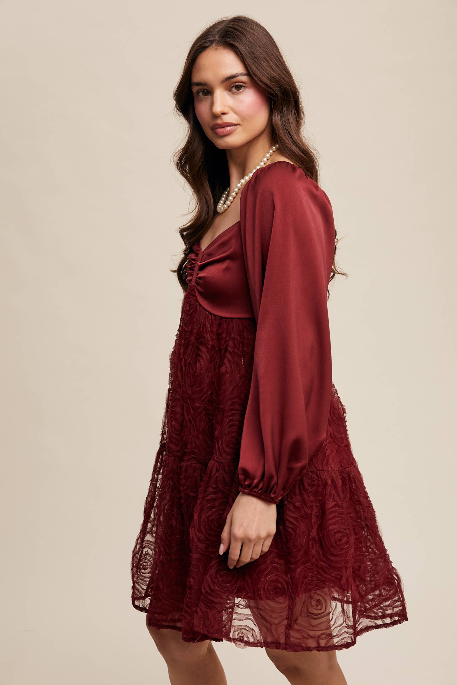 Side view of Model wearing oxblood red rosette mini dress with ruched sweetheart neckline, puff long sleeves, and tiered lace skirt — elegant and romantic look.