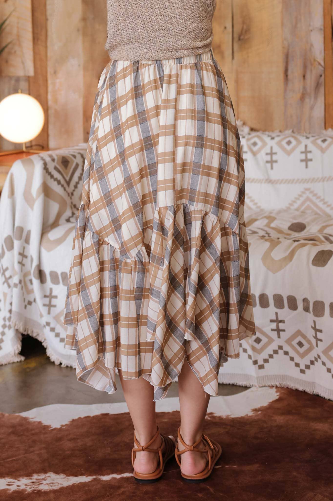 Person wearing a plaid skirt standing in a room with patterned furniture.