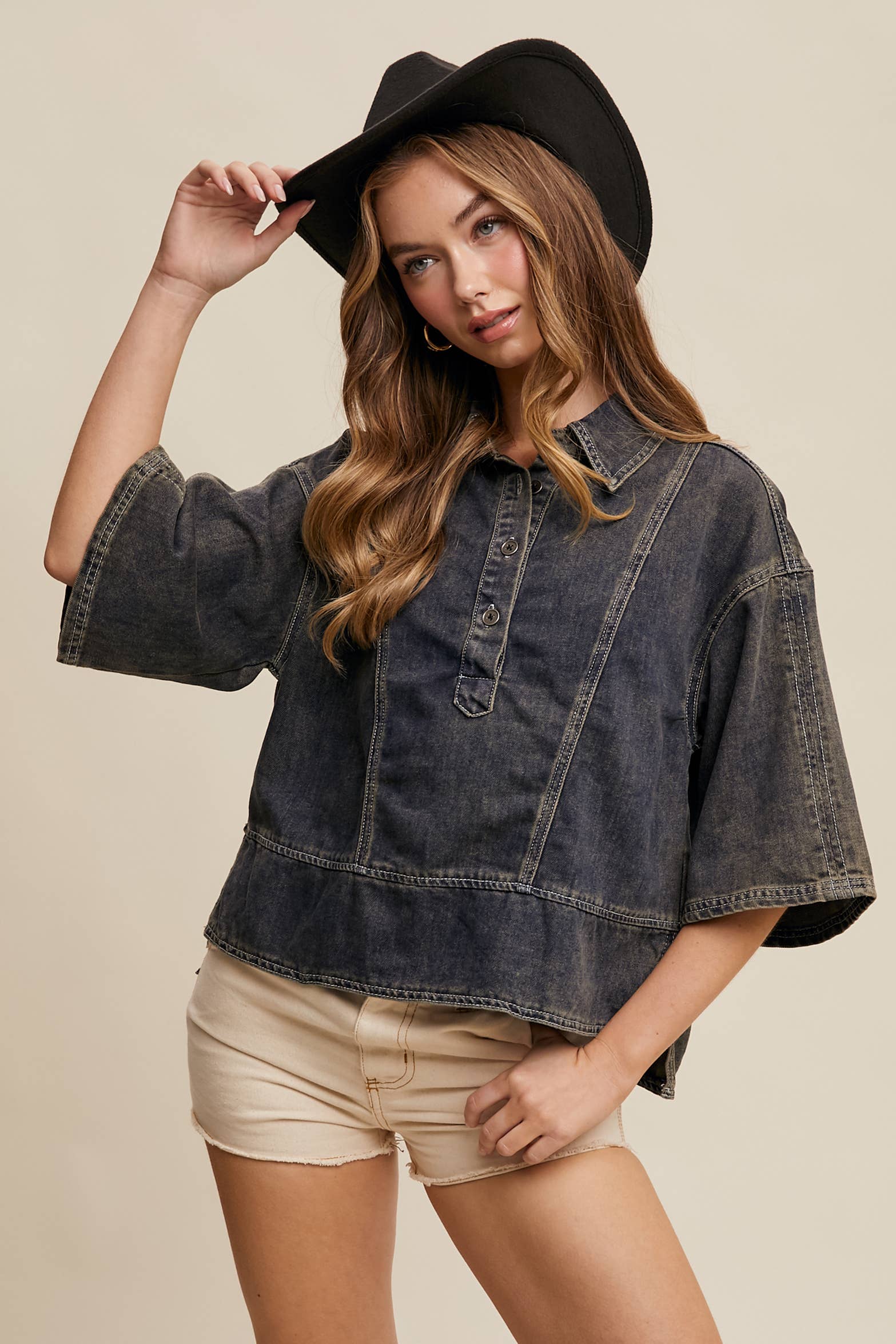 Dark-wash denim pullover top with half-button placket, exposed seam panels, and wide elbow-length sleeves in a relaxed, boxy fit.