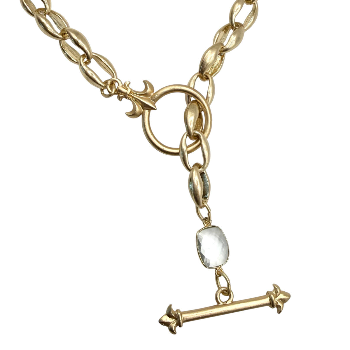 A gold-tone chain necklace with a toggle clasp and a dangling bar pendant featuring a small clear faceted stone, shown on a plain white background.
