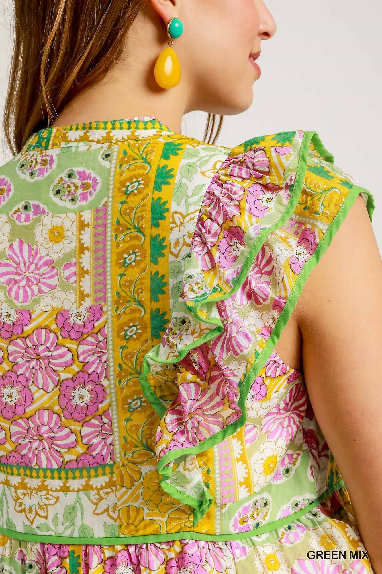 Close-up of a colorful floral dress with ruffled details on a plain background