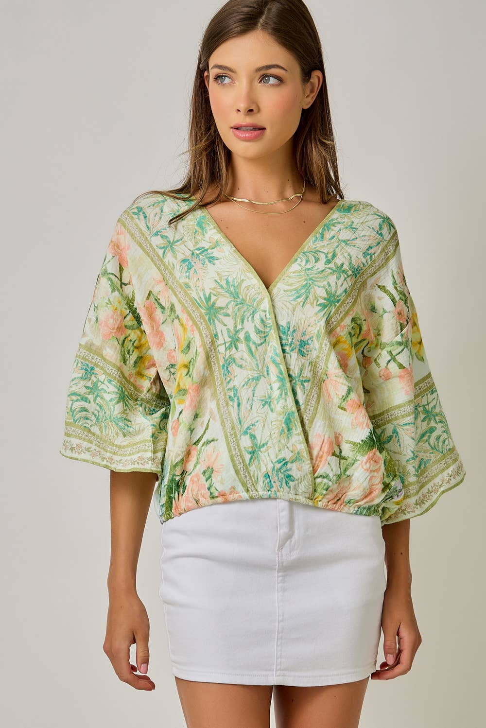 Woman wearing a floral kimono-style top with a plain background