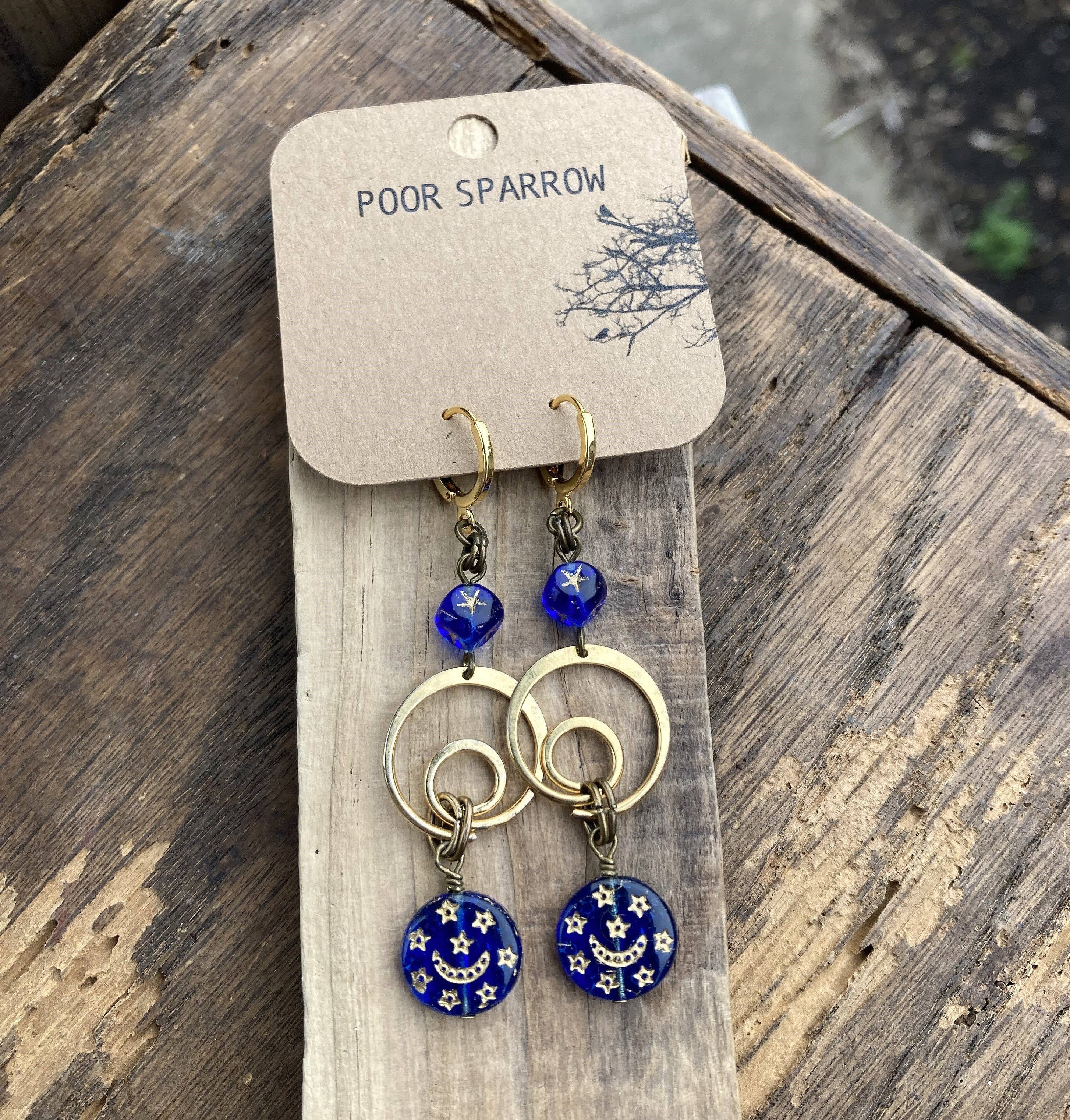 Artisan dangle earrings featuring gold rings, blue glass beads, and night sky charms.