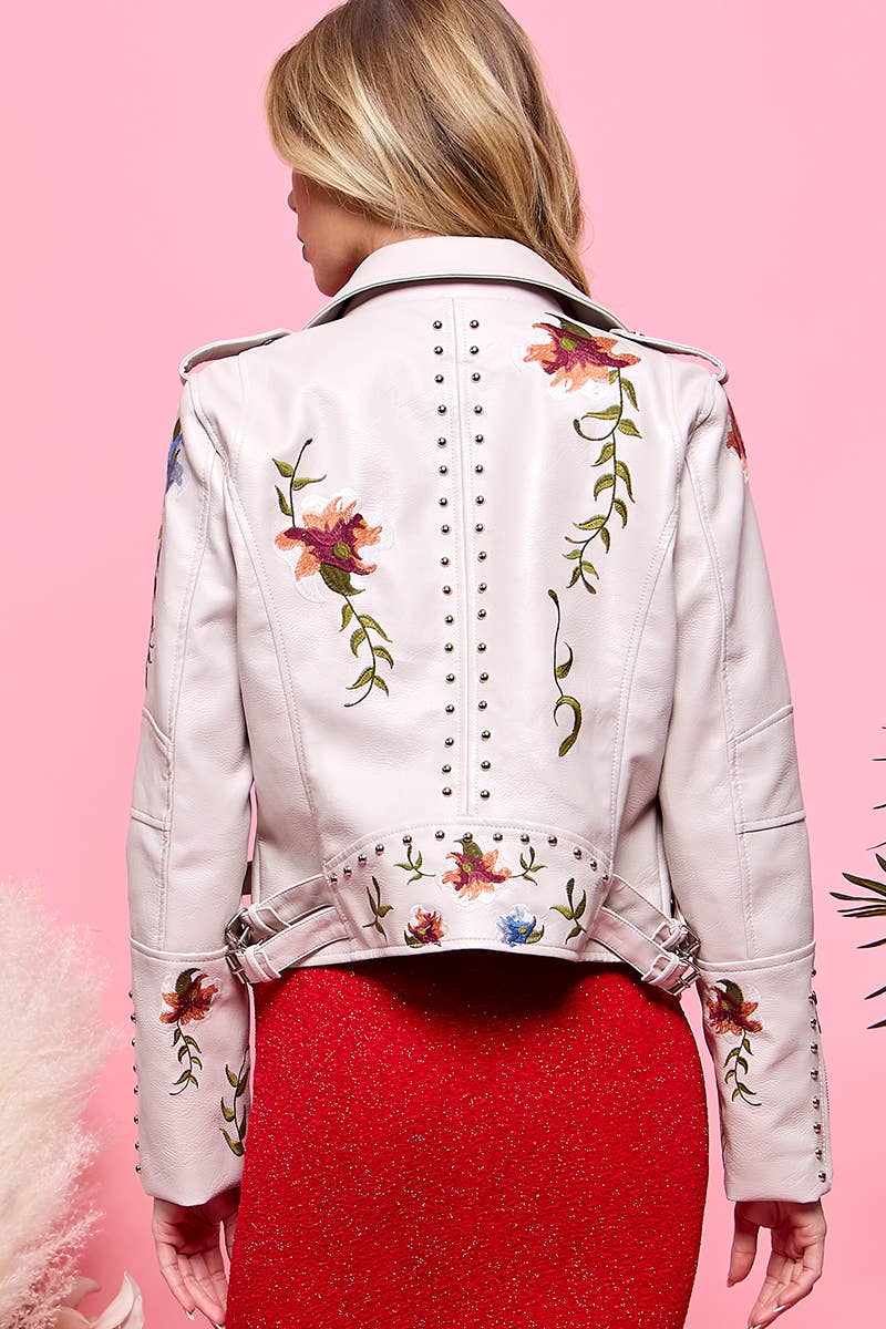 Back view of cream faux-leather moto jacket with floral embroidery and stud trim, worn over a red dress.