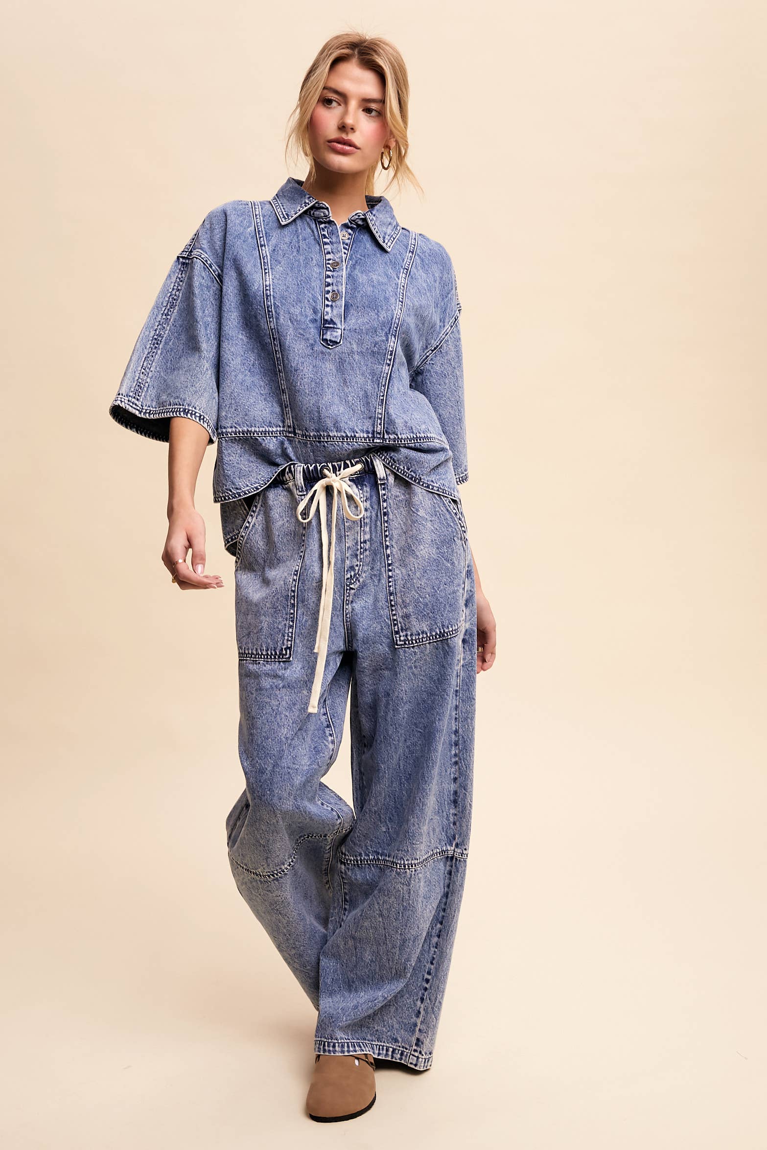 Light-wash denim pullover top with a half-button placket, exposed seam panels, and wide elbow-length sleeves in a relaxed, boxy fit.