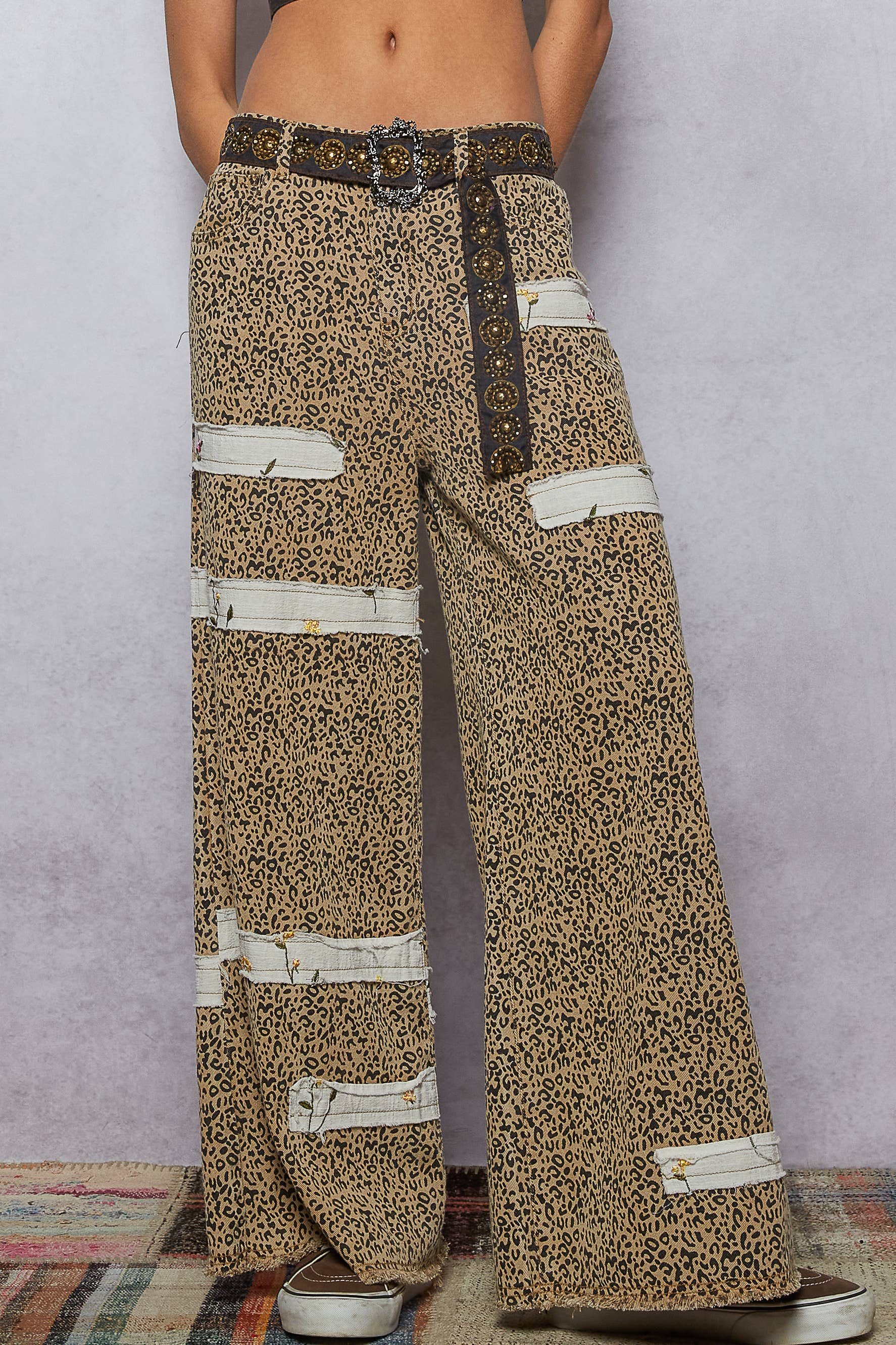 Fashion belt featuring bold gold studs and decorative buckle, styled with patterned jeans.