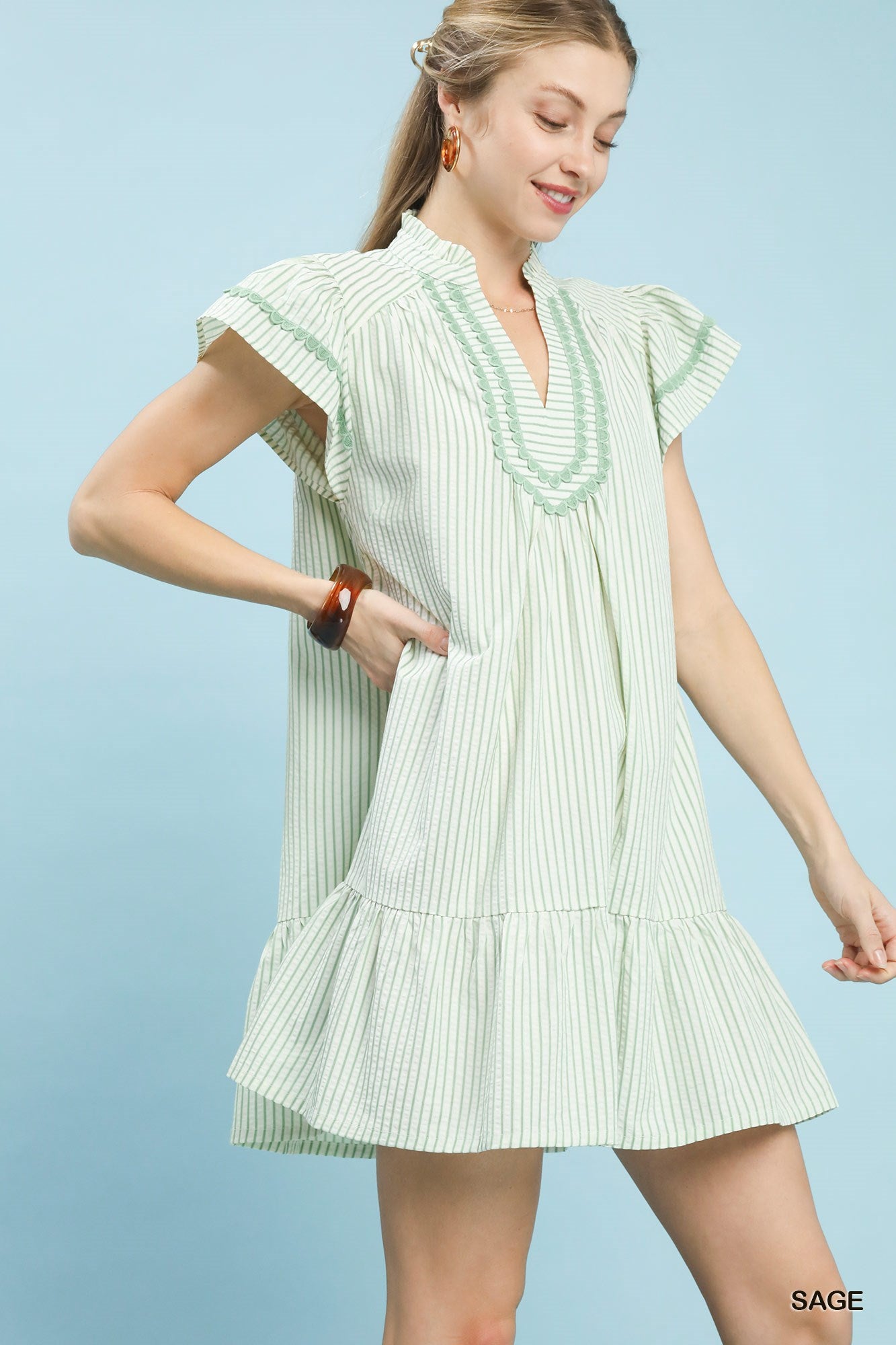 Woman wearing a light green and white striped dress against a light blue background