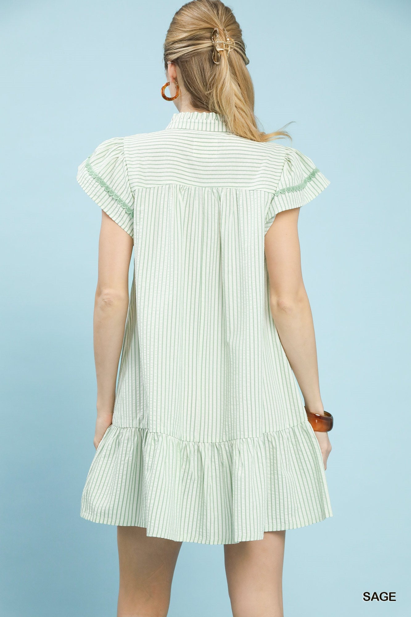 Woman wearing a light green and white striped dress against a light blue background