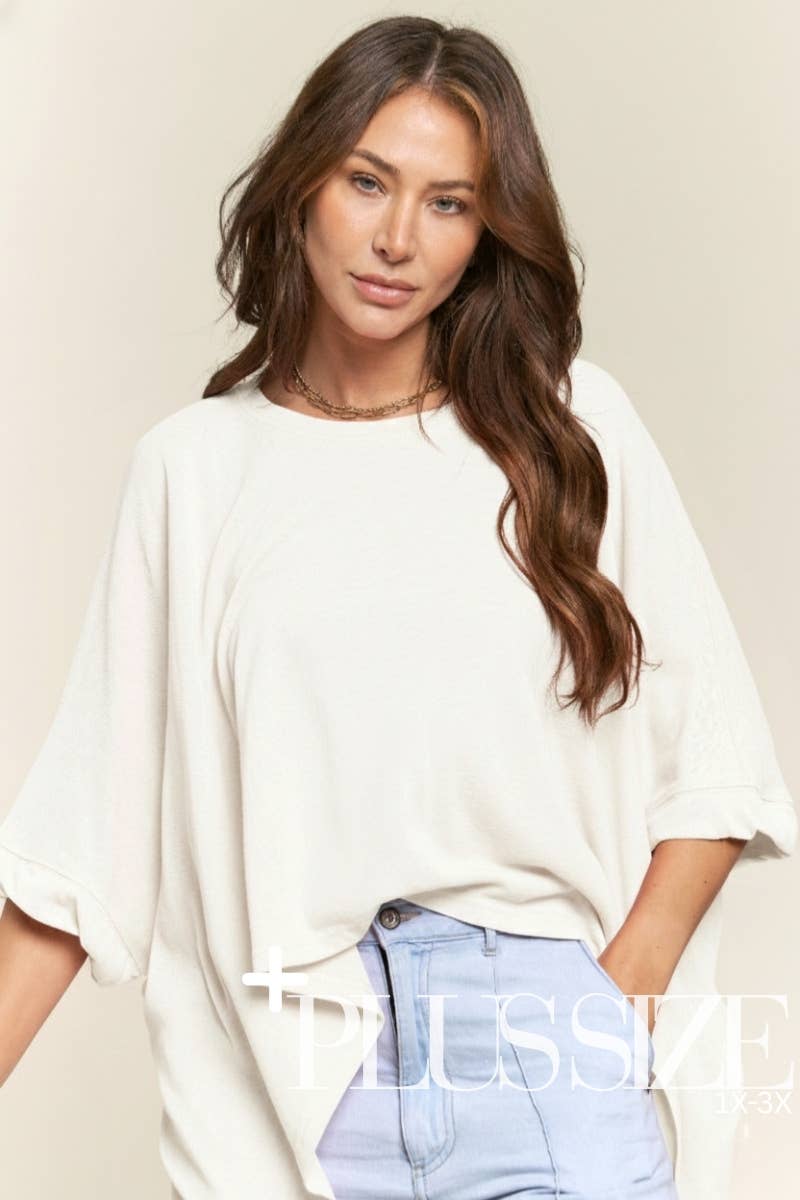 Woman wearing a white oversized shirt and light blue jeans on a beige background