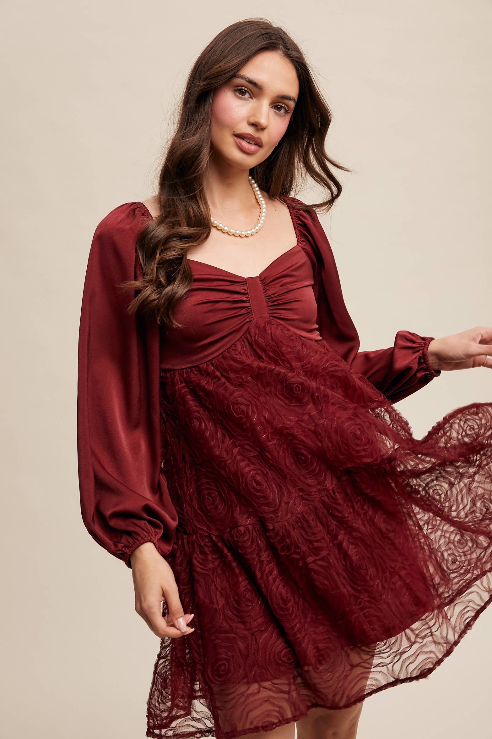 Model wearing oxblood red rosette mini dress with ruched sweetheart neckline, puff long sleeves, and tiered lace skirt — elegant and romantic look.