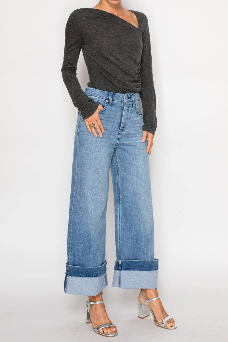 Model wearing ultra high-rise wide-leg jeans in medium stone wash with 5-inch cuff detail, styled with heels — modern cropped denim.