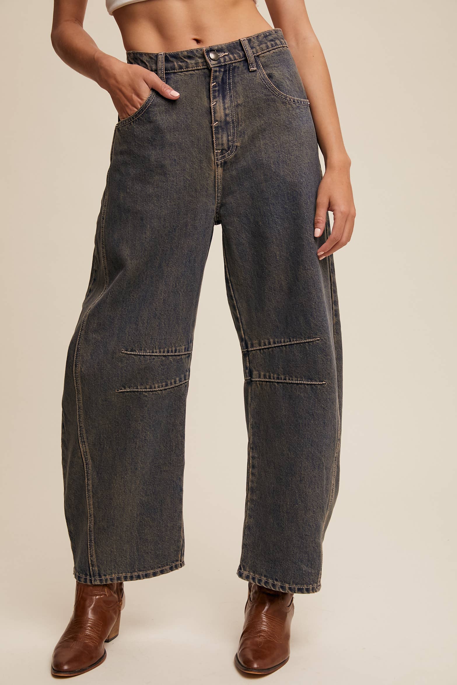 Dark wash wide-leg jeans with relaxed fit, seam detailing across the knees, and a high-rise waist, styled with brown ankle boots.