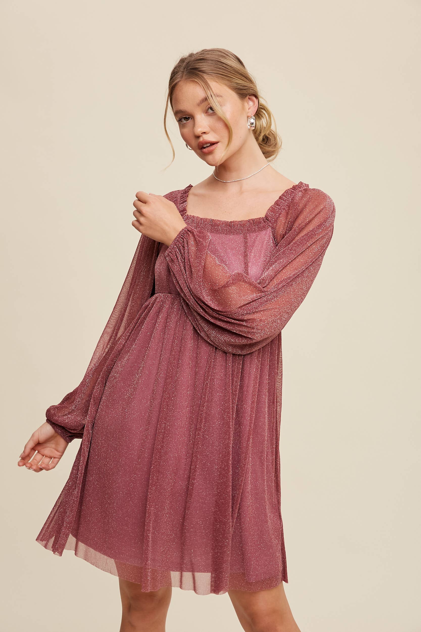 Model wearing a mauve shimmer mini dress with long sheer sleeves, square neckline, and flowy A-line silhouette — romantic sparkle party dress