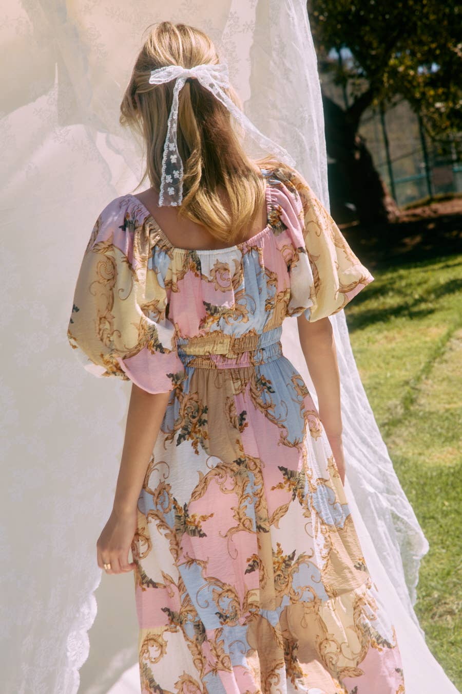 Woman wearing a floral dress with puffed sleeves in an outdoor setting