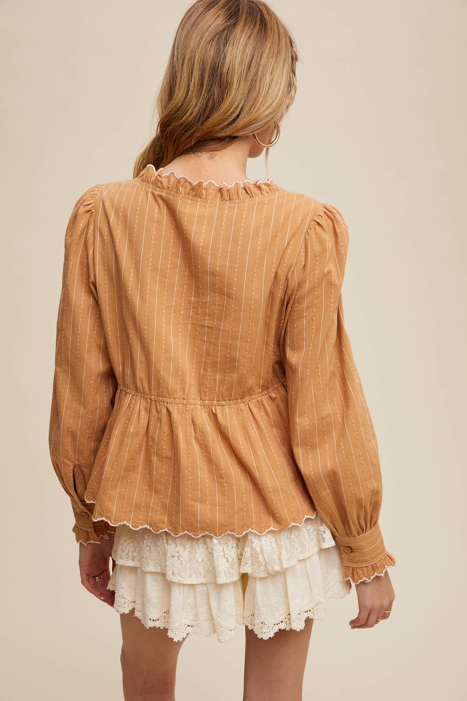 Back view- Side view- Camel pinstripe blouse with ruffled neckline, white rose embroidery, puff long sleeves, button front, and scalloped peplum hem—styled with white lace shorts.