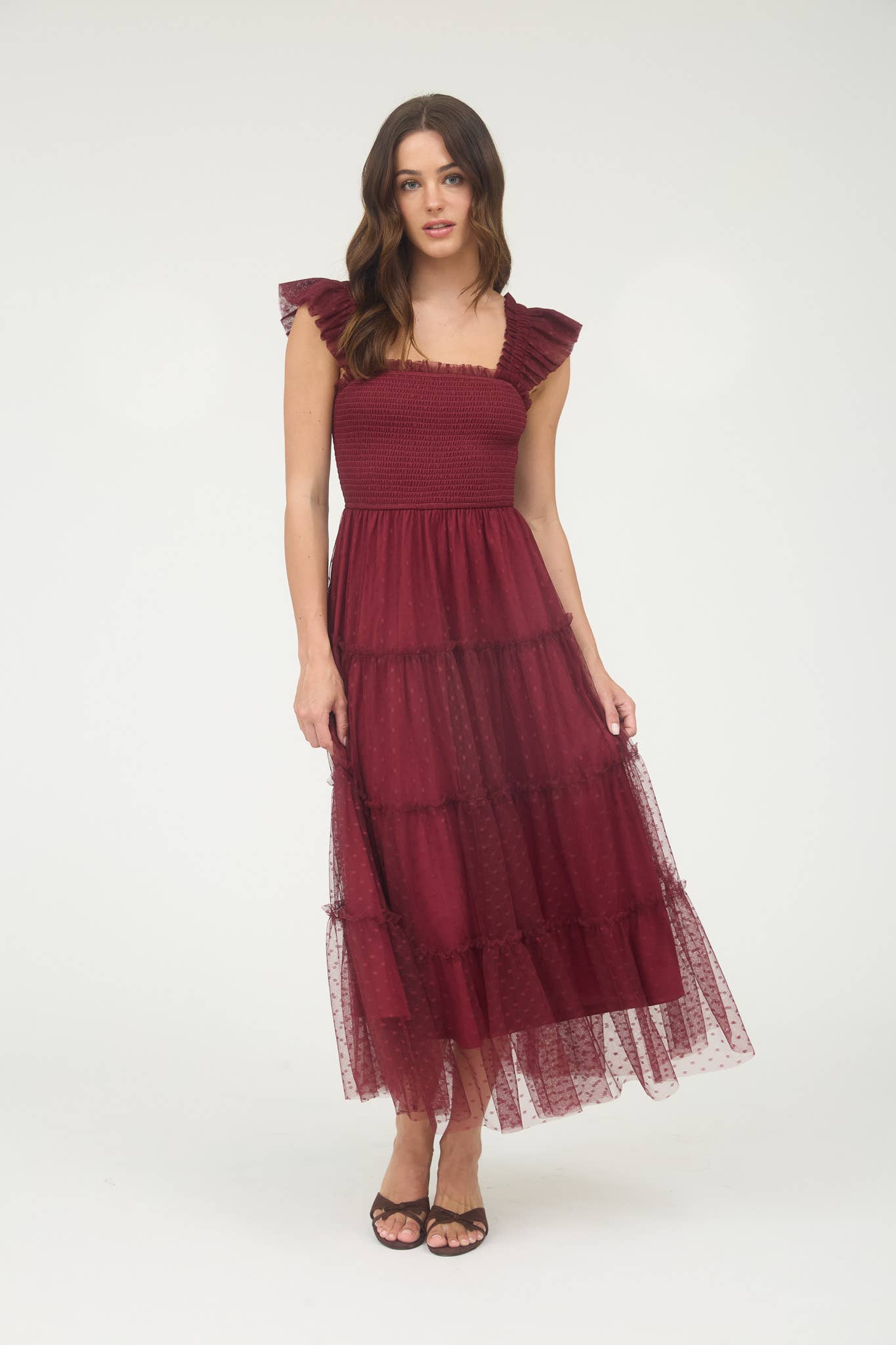 Model wearing burgundy smocked midi dress with ruffle sleeves, tiered dotted mesh overlay, and flowy A-line silhouette.