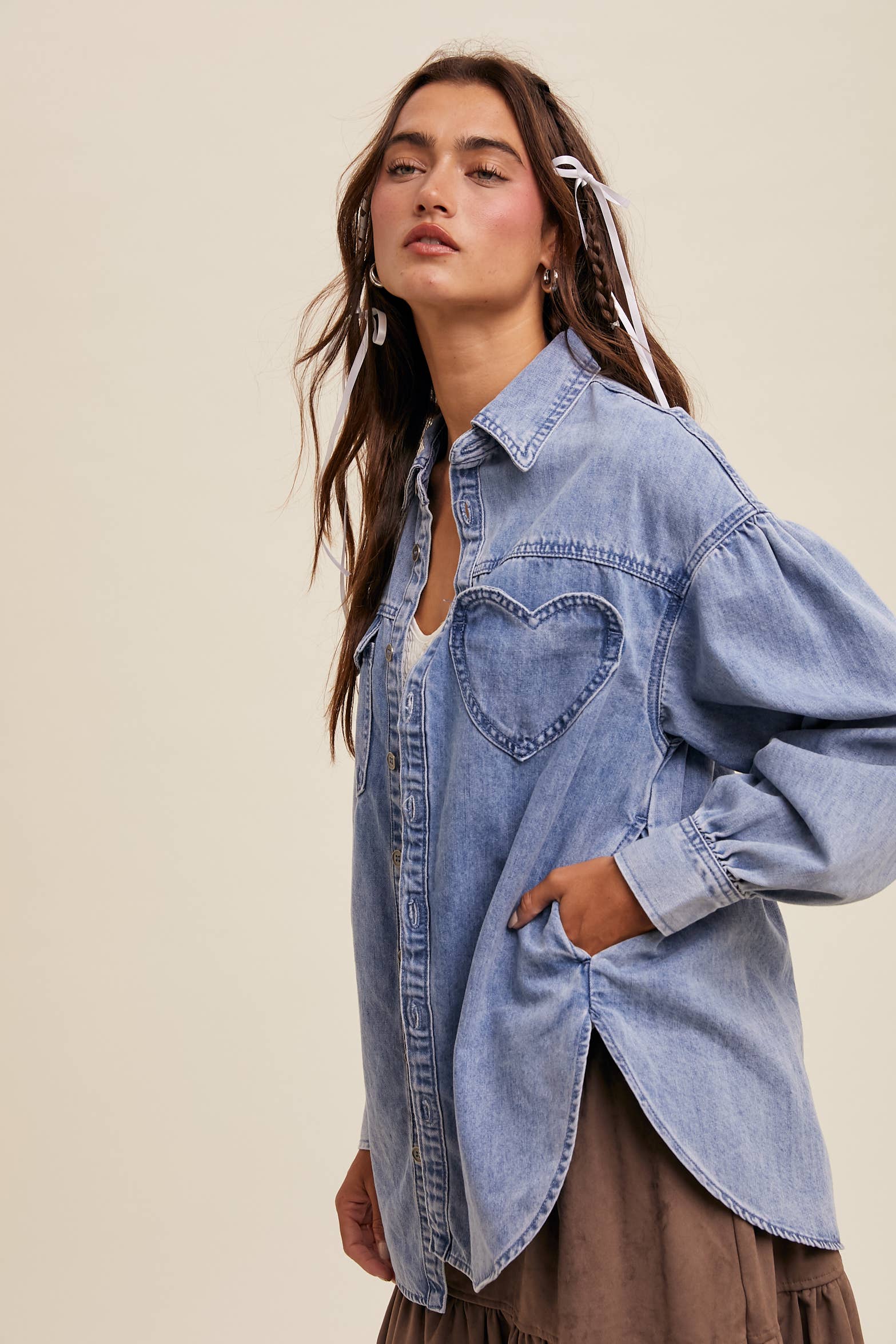 Side view- Light-wash oversized denim shacket with a heart-shaped chest pocket, button front, drop shoulders, balloon sleeves, and a curved hem.