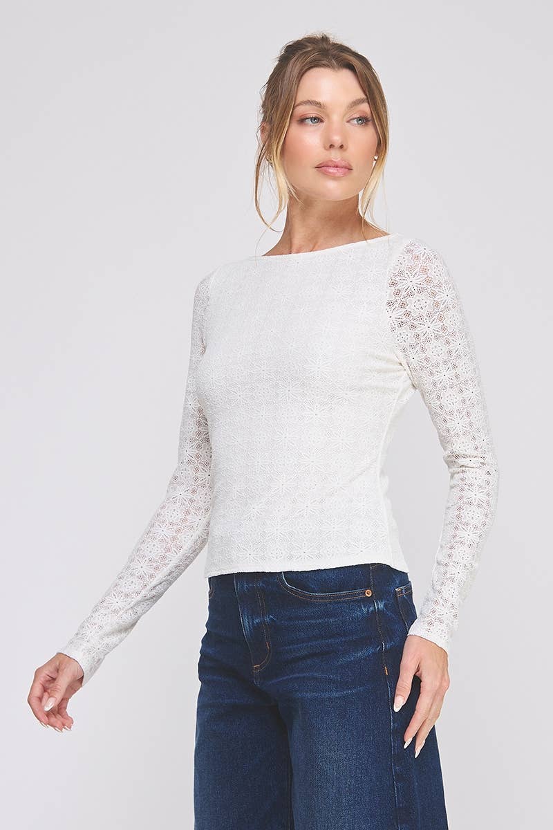 Woman wearing a white long-sleeve top with lace details and blue jeans on a light gray background