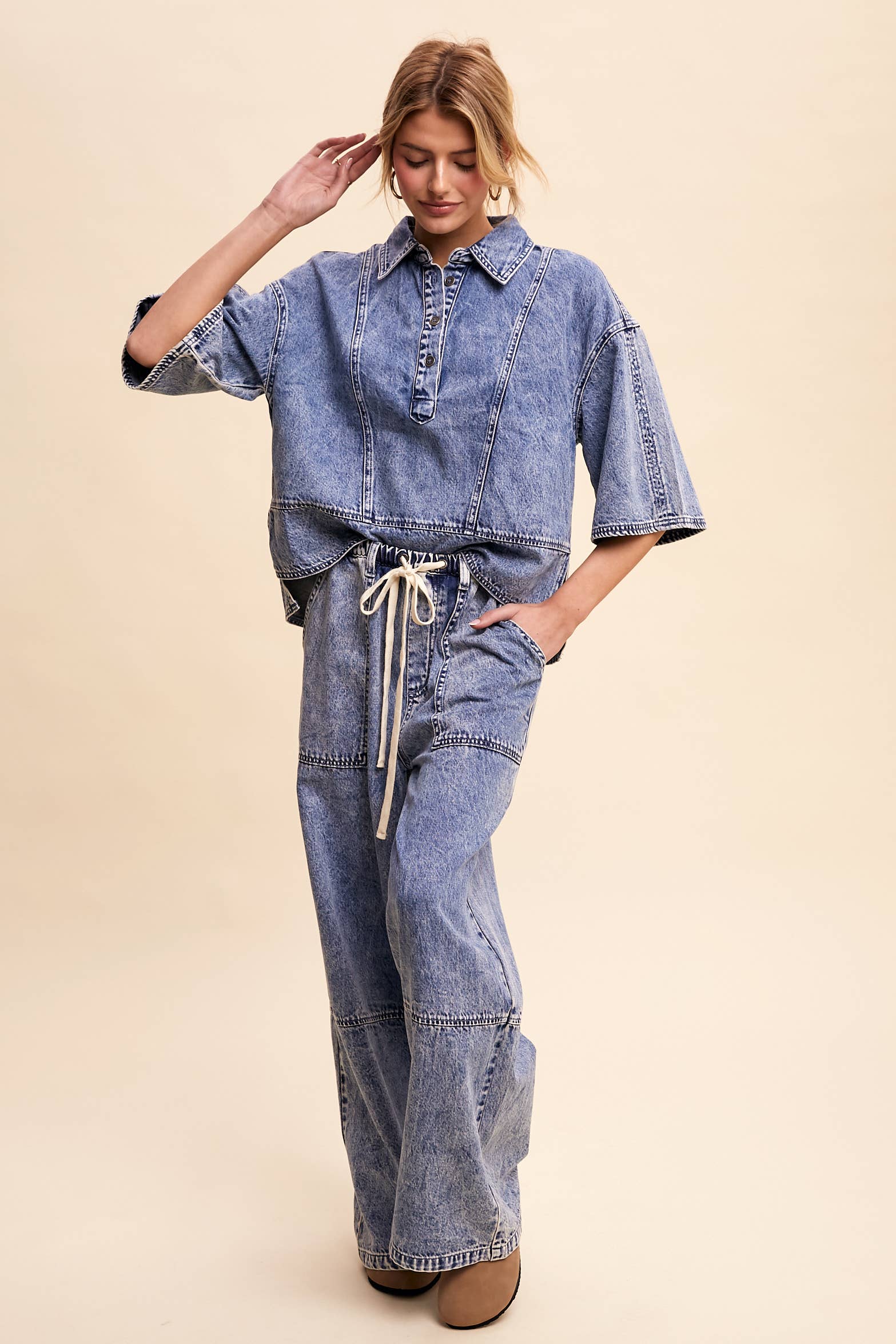 Light-wash denim pullover top with a half-button placket, exposed seam panels, and wide elbow-length sleeves in a relaxed, boxy fit.