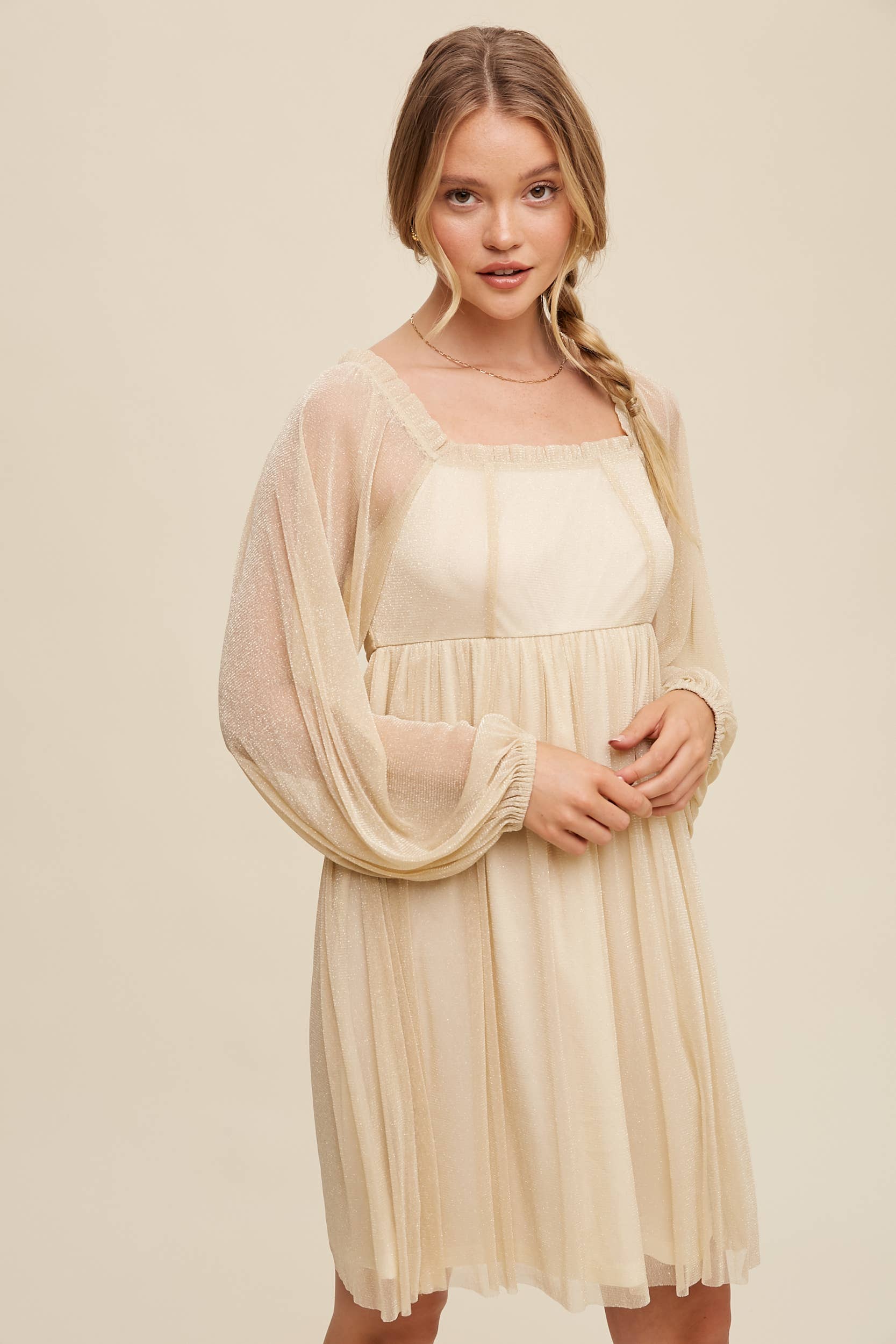 Model wearing a beige shimmer mini dress with long sheer sleeves, square neckline, and flowy A-line silhouette — romantic sparkle party dress