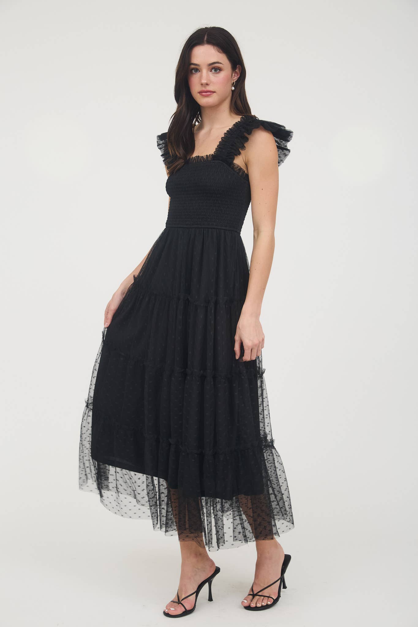 Model wearing black smocked midi dress with ruffle sleeves, tiered dotted mesh overlay, and flowy A-line silhouette.