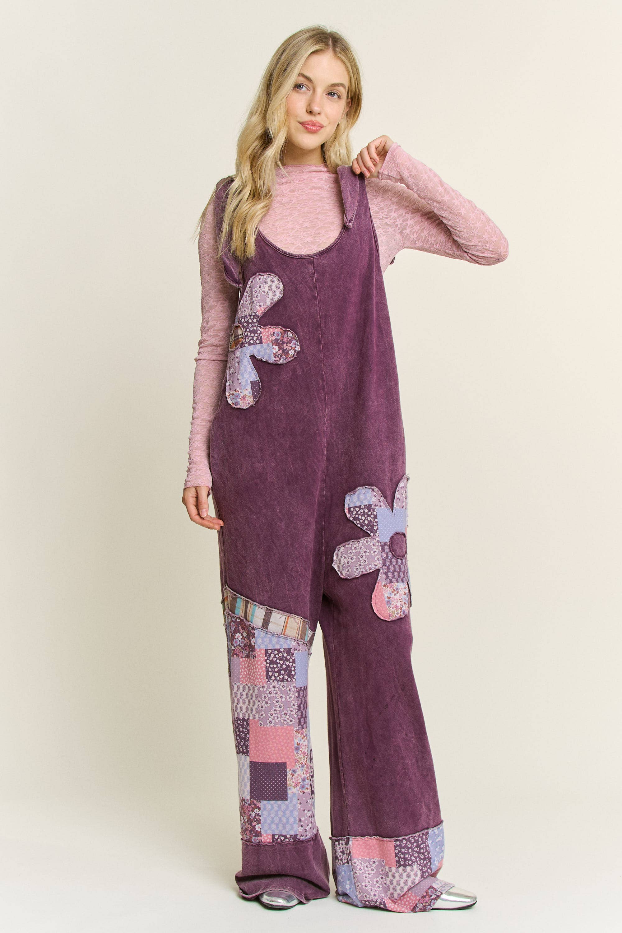 Woman wearing boho patchwork mineral-wash jumpsuit with daisy appliqués and wide legs