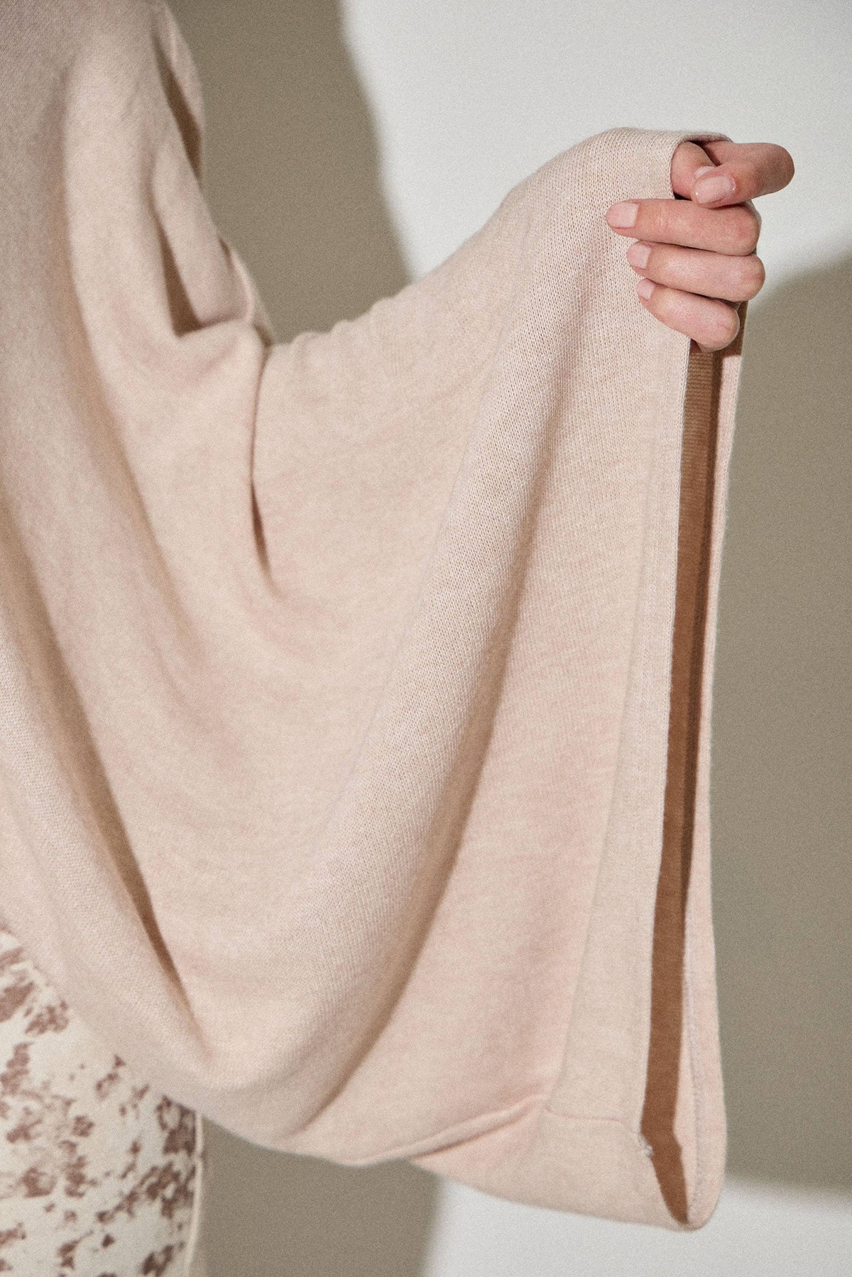 Beige fabric held by a hand against a neutral background