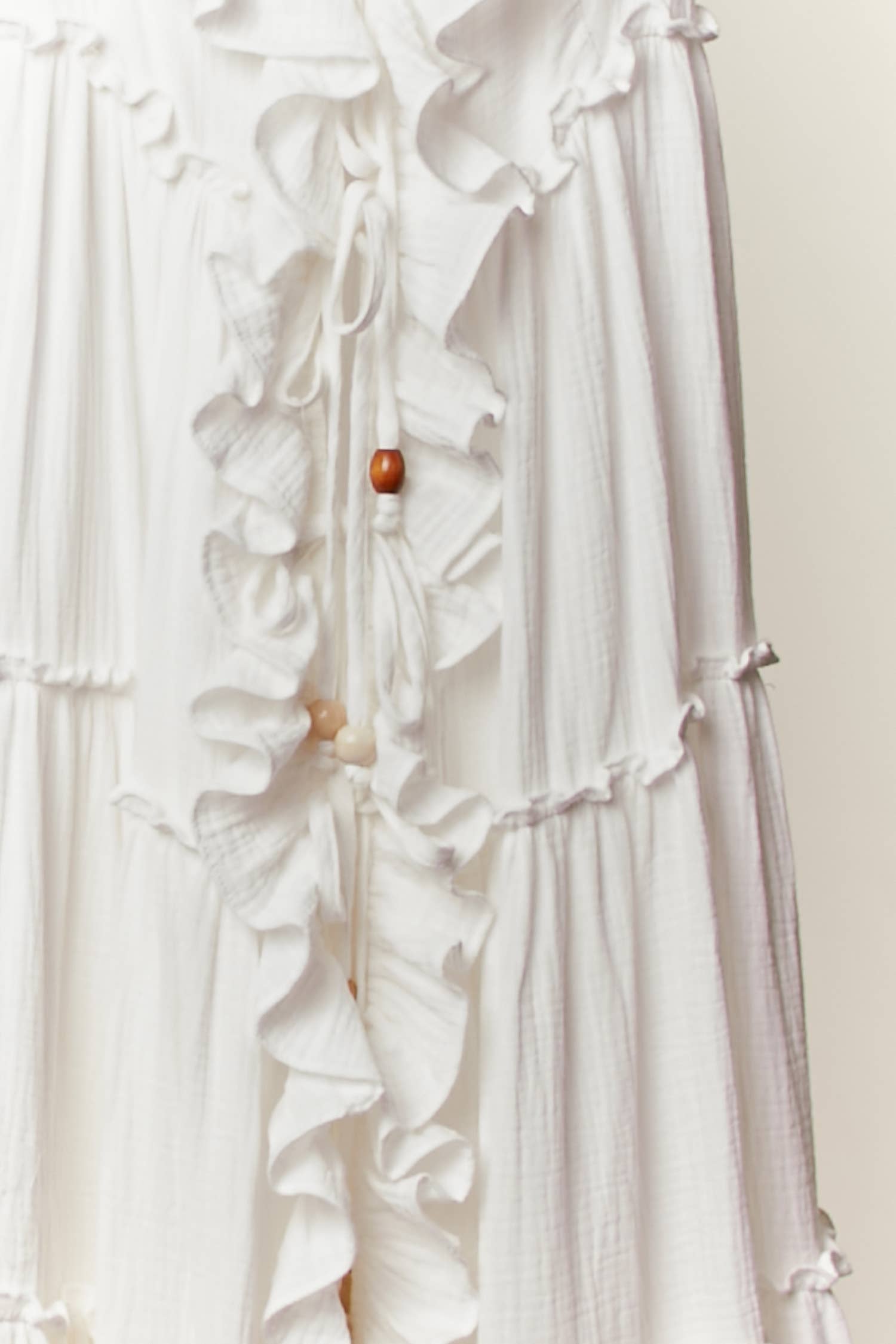 Cream ruffle cardigan dress detail - close-up of luxurious flowing fabric and cascading ruffle construction