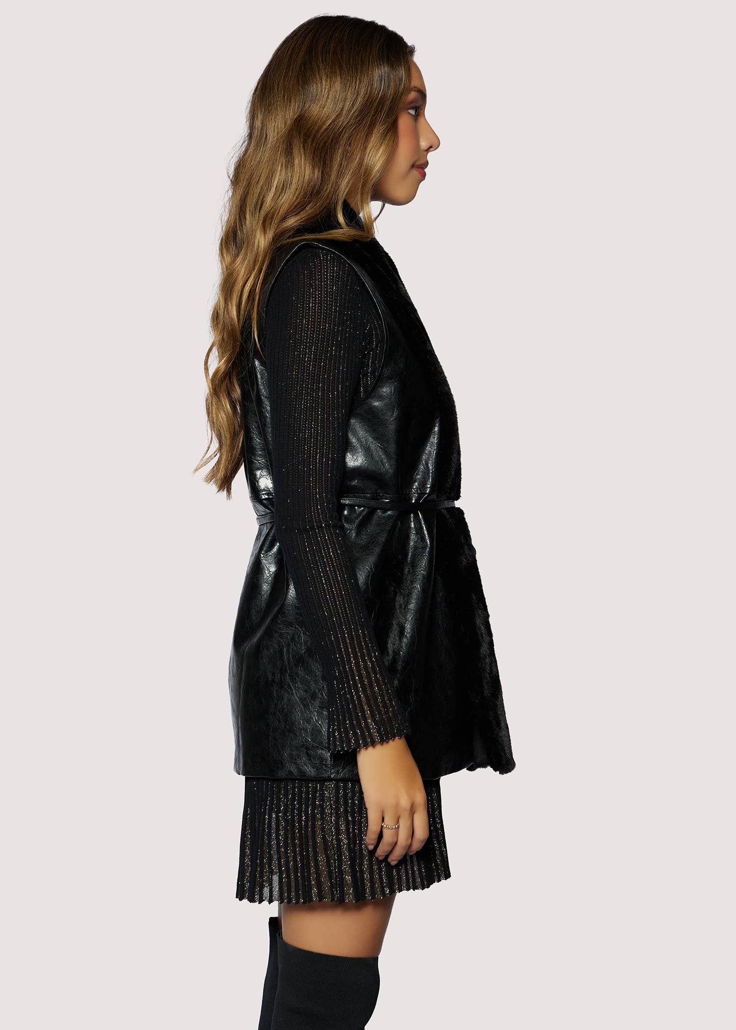 Woman wearing a black leather vest over a black dress with a white background