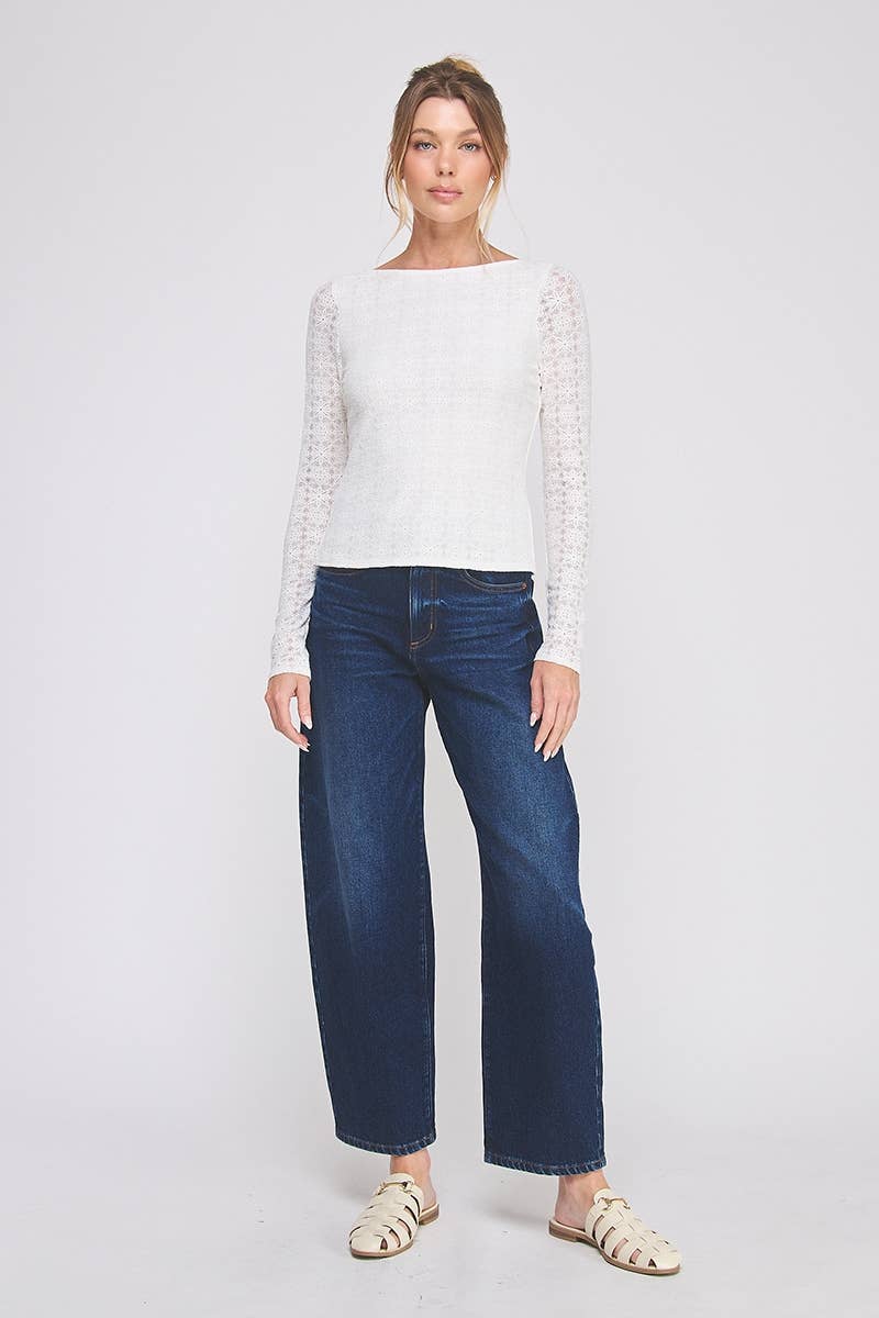 Woman wearing a white top with lace details and blue jeans on a white background