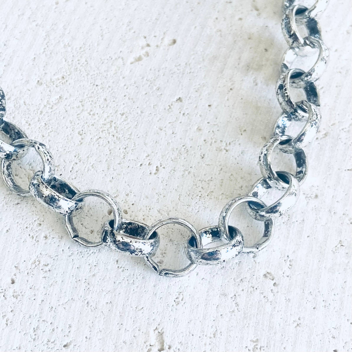 Silver chain bracelet on a textured white background