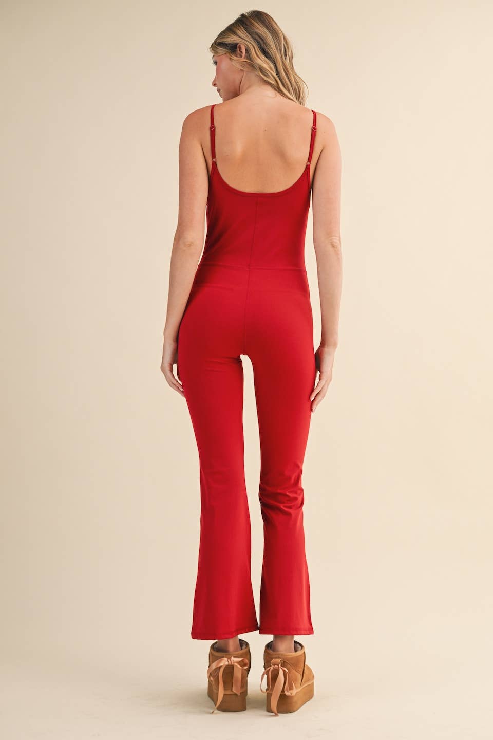 ear view of Woman wearing Kimberly C flare jumpsuit in red with scoop neckline and flared leg.