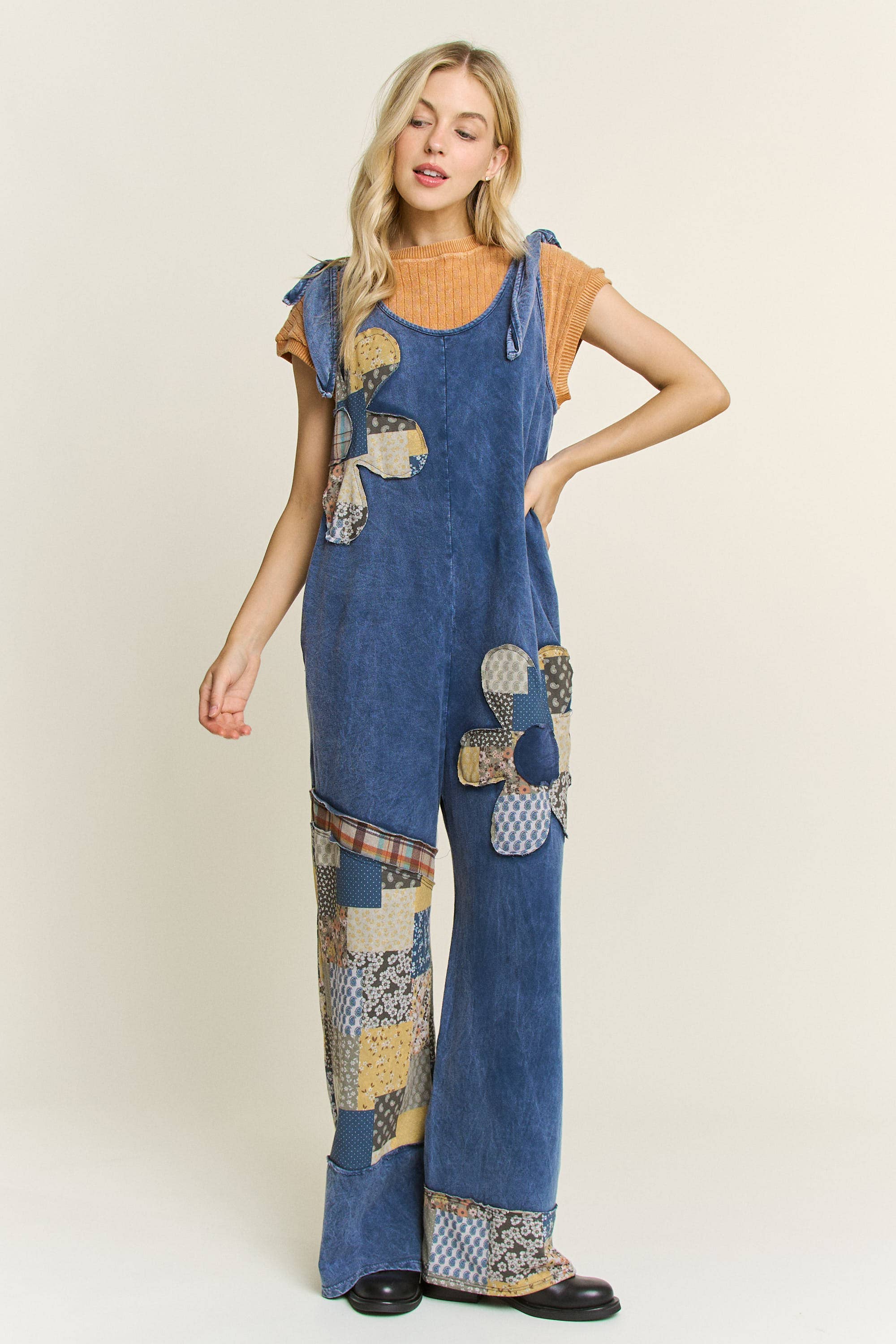 Woman wearing boho patchwork mineral-wash jumpsuit in blue with daisy appliqués and wide legs