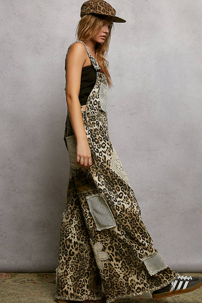 Side view of model wearing Boho leopard print patchwork overalls featuring wide legs, crochet lace appliqué details, and distressed accents. Styled with a leopard hat and black crop top for a trendy, eclectic look.