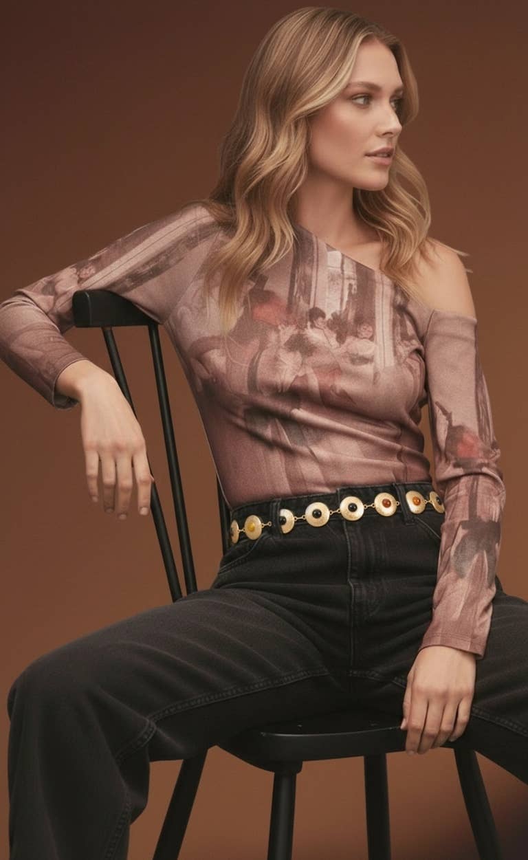 Woman sitting on a chair wearing a sheer top with floral patterns and black pants.