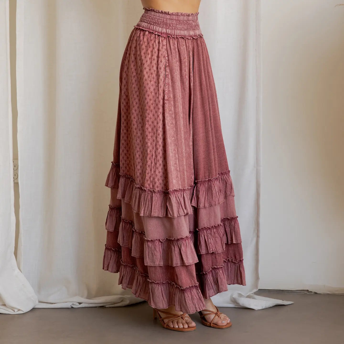 Garnet Artisan Panel Maxi Skirt - side view showing smocked waist, mixed texture panels, and layered ruffle hem styled with strappy sandals