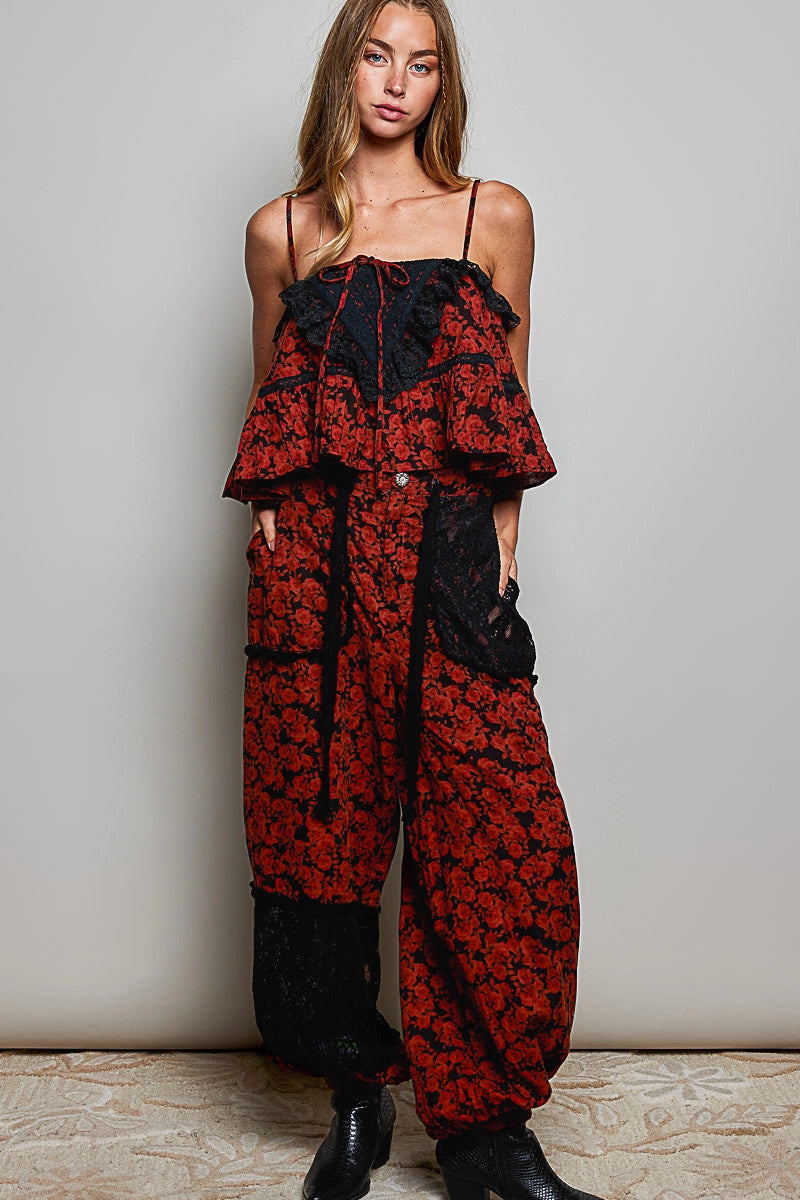 Woman wearing a red and black floral jumpsuit with a plain background