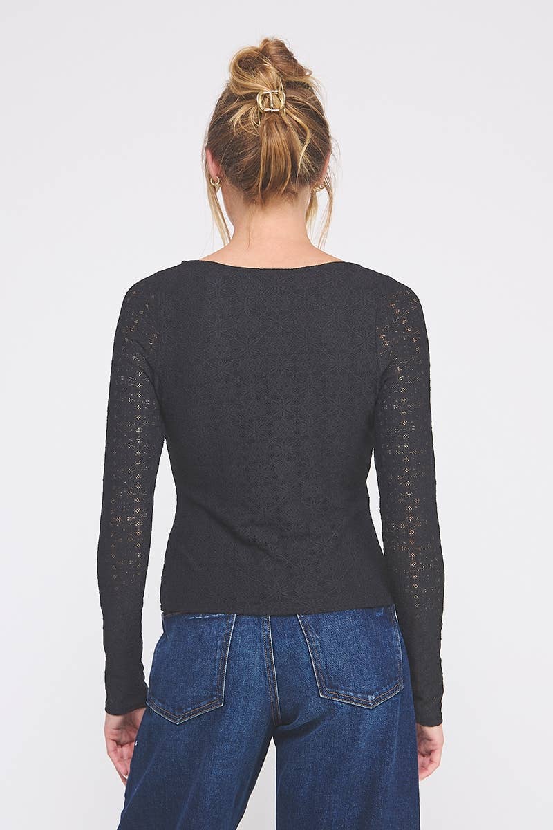 Person wearing a black long-sleeve top with lace sheer sleeves against a white background