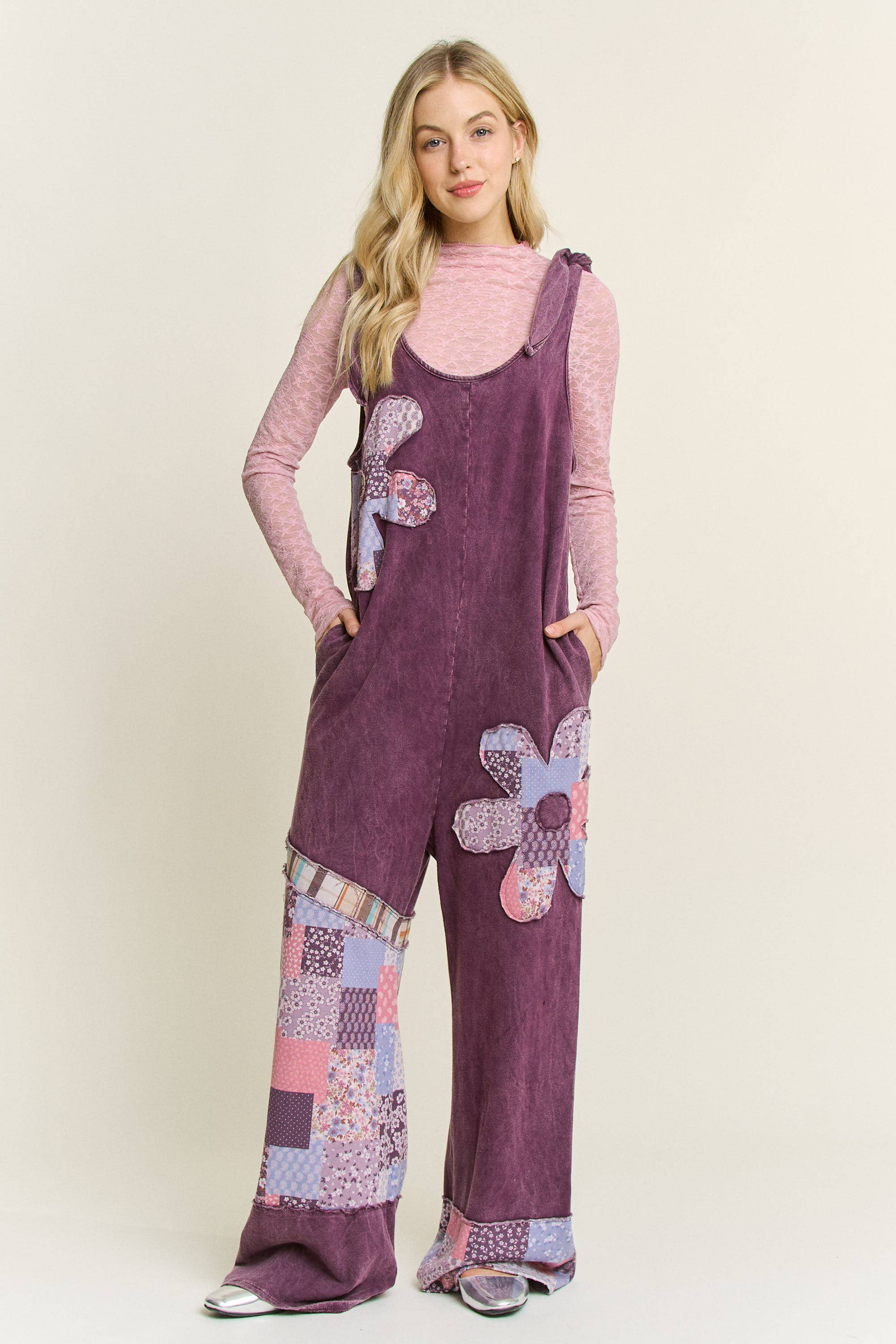 Woman wearing boho patchwork mineral-wash jumpsuit with daisy appliqués and wide legs
