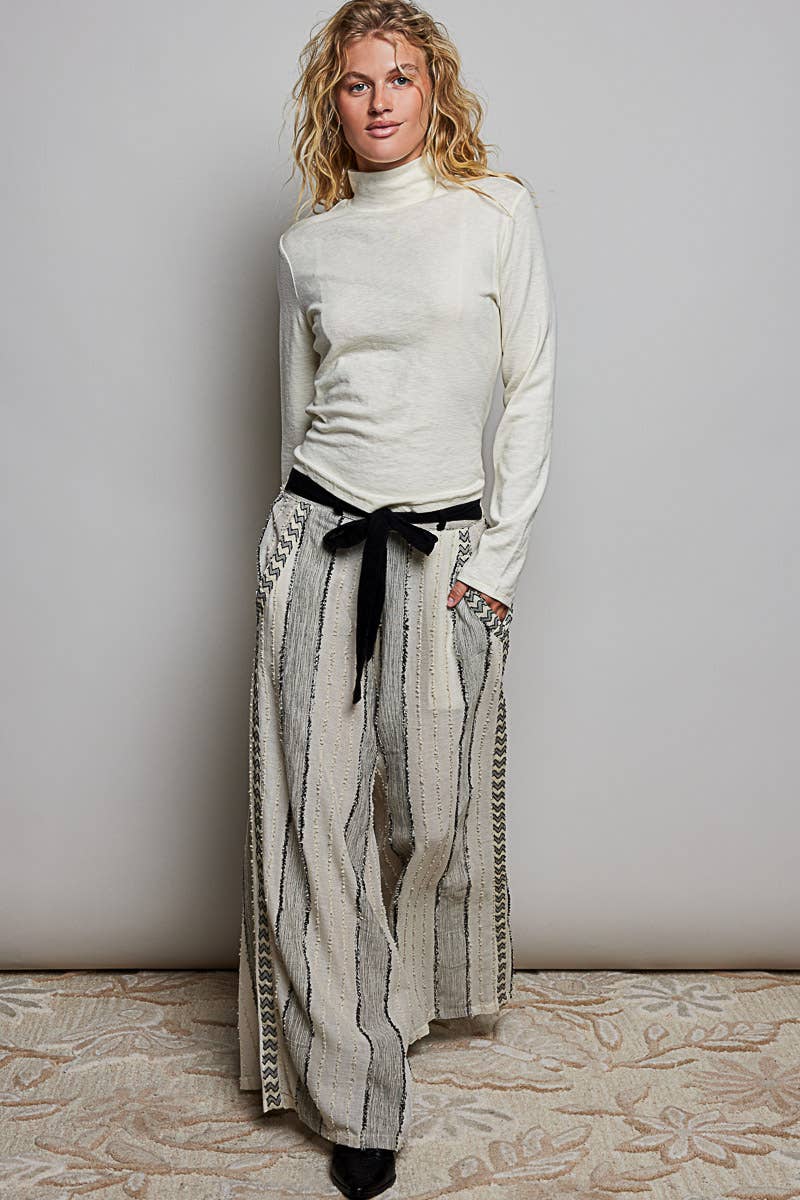 Woman wearing a white turtleneck and patterned skirt against a plain background