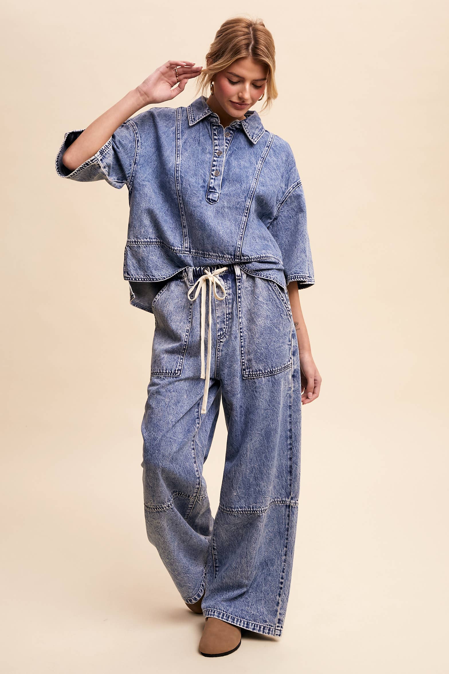 Light-wash denim pullover top with a half-button placket, exposed seam panels, and wide elbow-length sleeves in a relaxed, boxy fit.