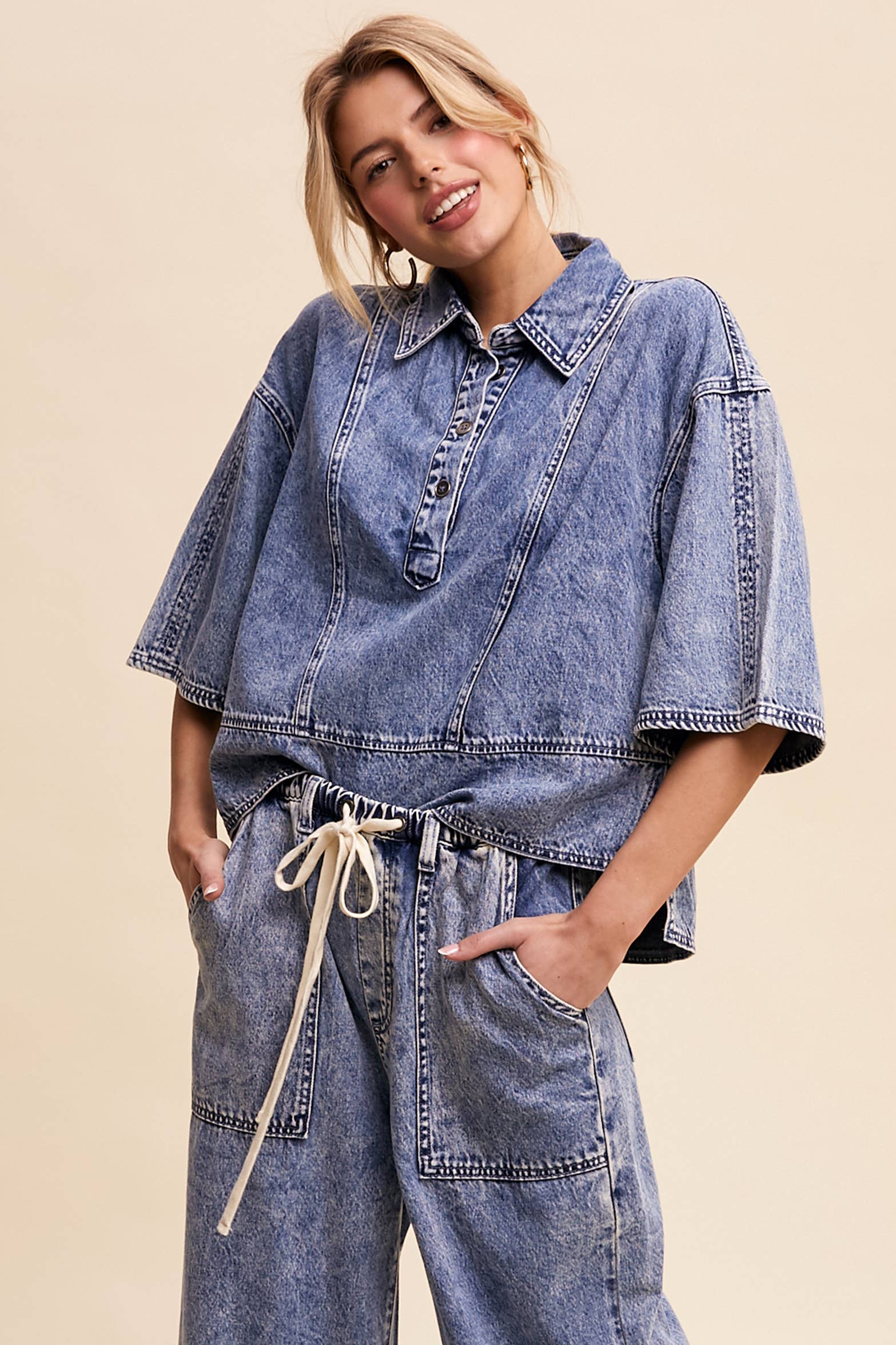 Light-wash denim pullover top with a half-button placket, exposed seam panels, and wide elbow-length sleeves in a relaxed, boxy fit.