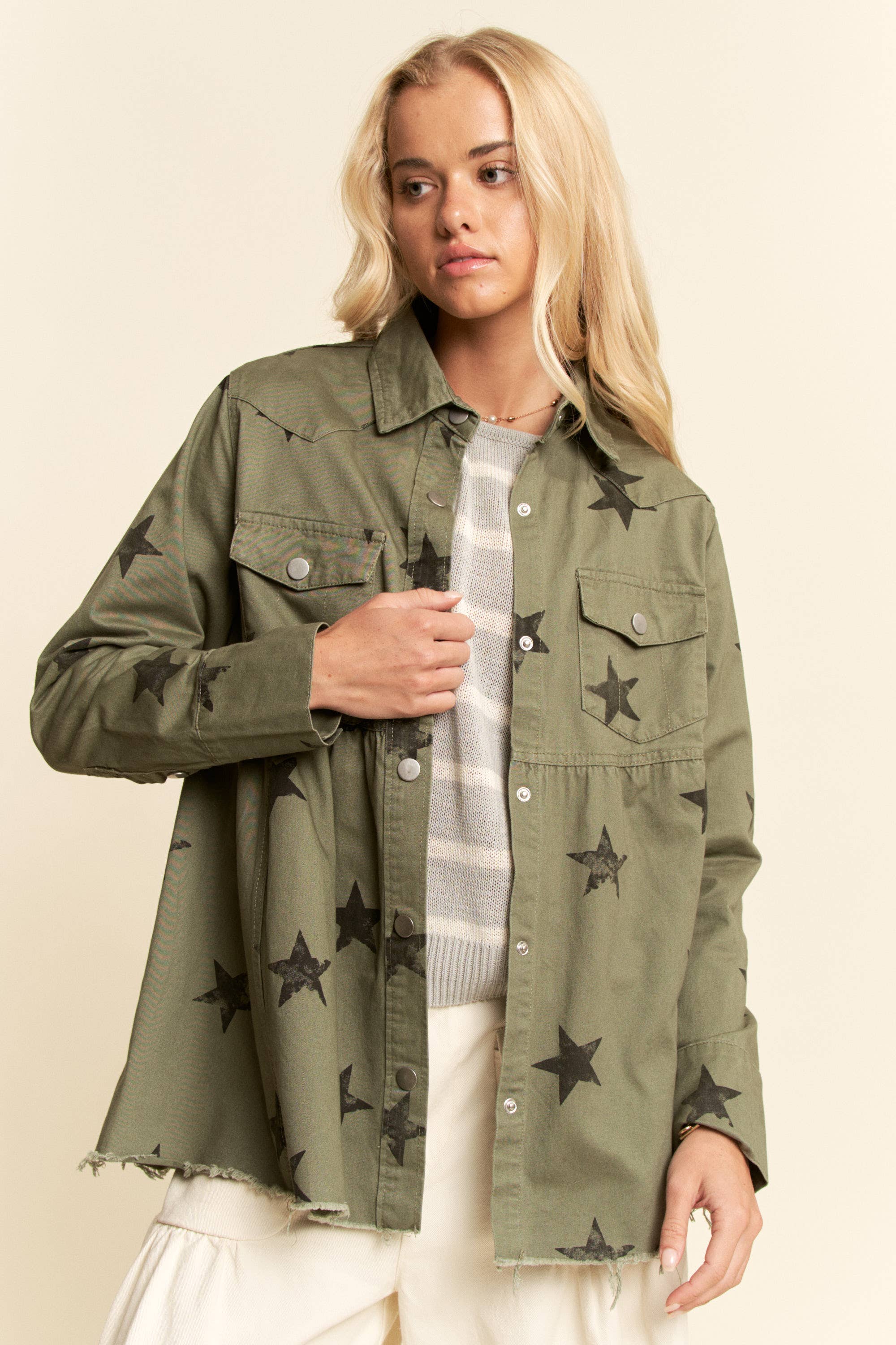 Olive star-print babydoll shacket with snap-button front, chest flap pockets, dropped shoulders, relaxed fit, and frayed curved hem.