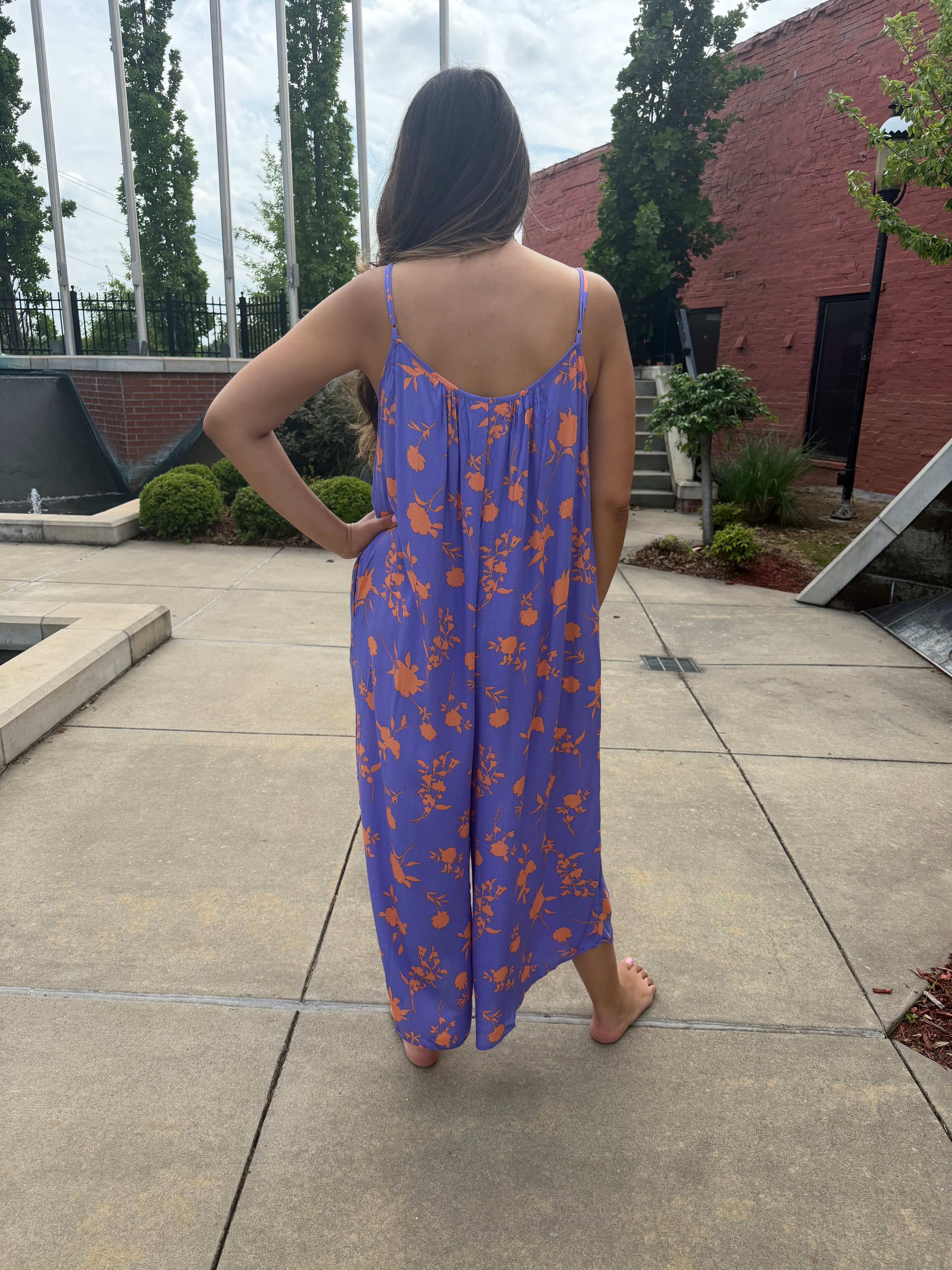 Person wearing a blue dress with orange patterns on a concrete patio.