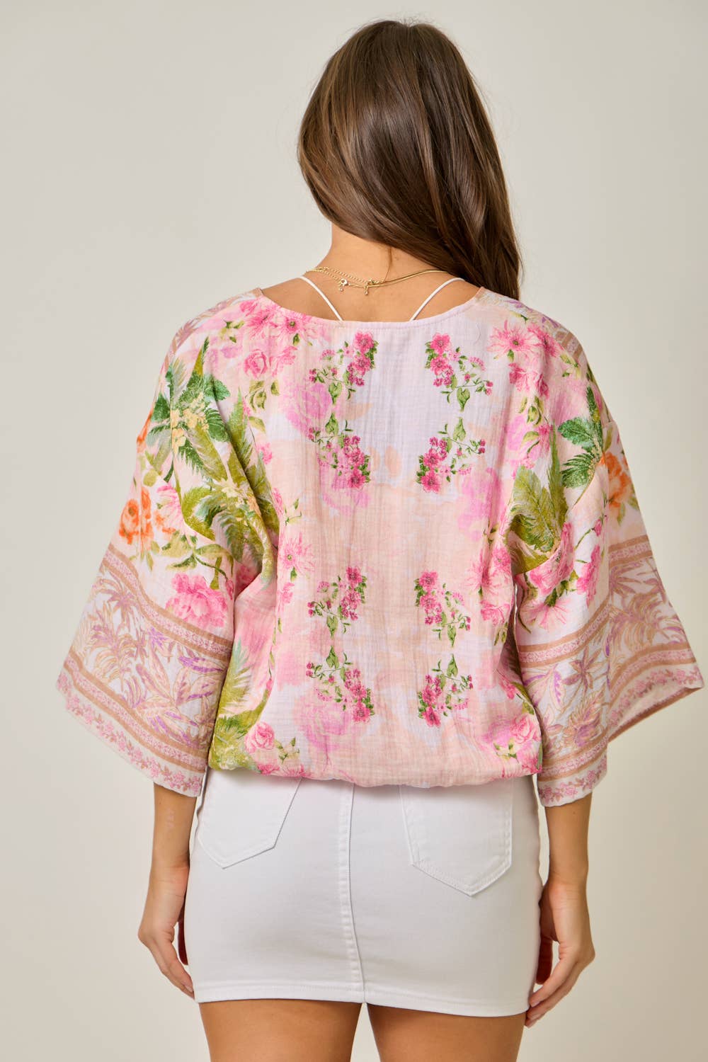 Woman wearing a floral blouse back view with a plain background