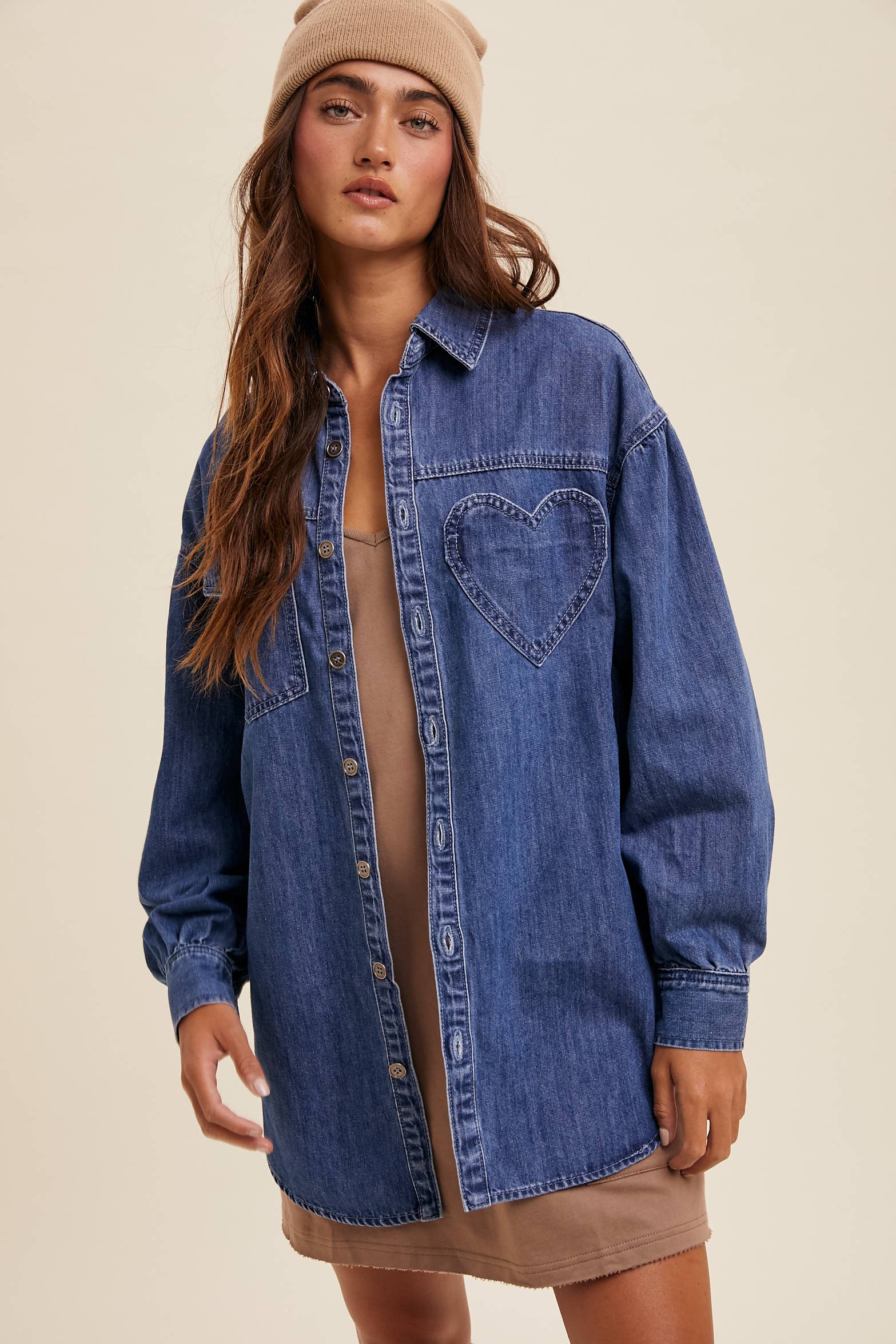 Medium-wash oversized denim shacket with button front, drop shoulders, balloon sleeves, side pockets, and a curved shirttail hem with side slits.