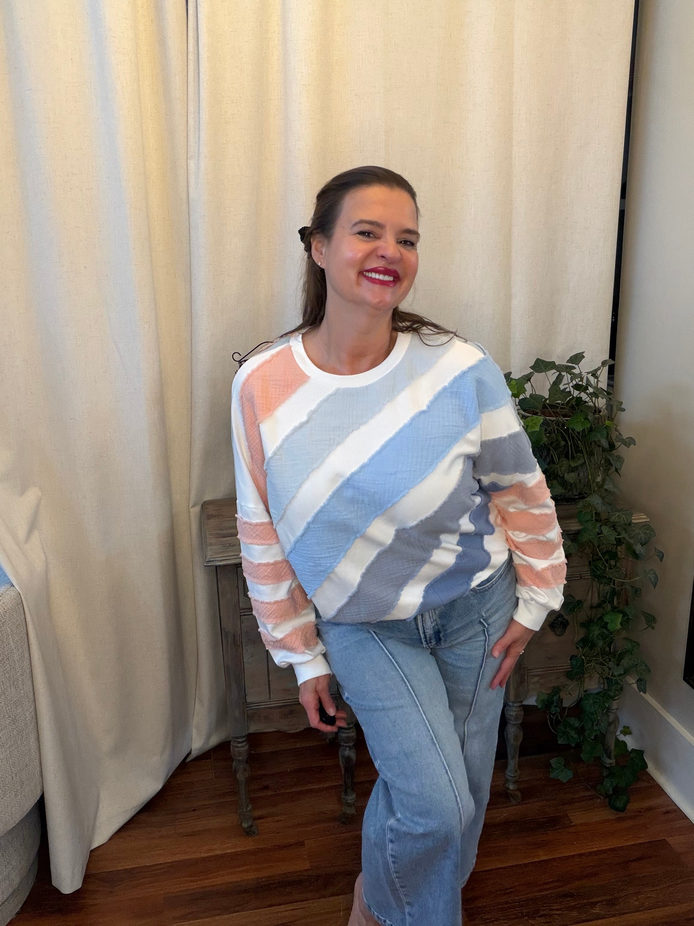 Woman wearing a colorful striped sweater and jeans indoors.