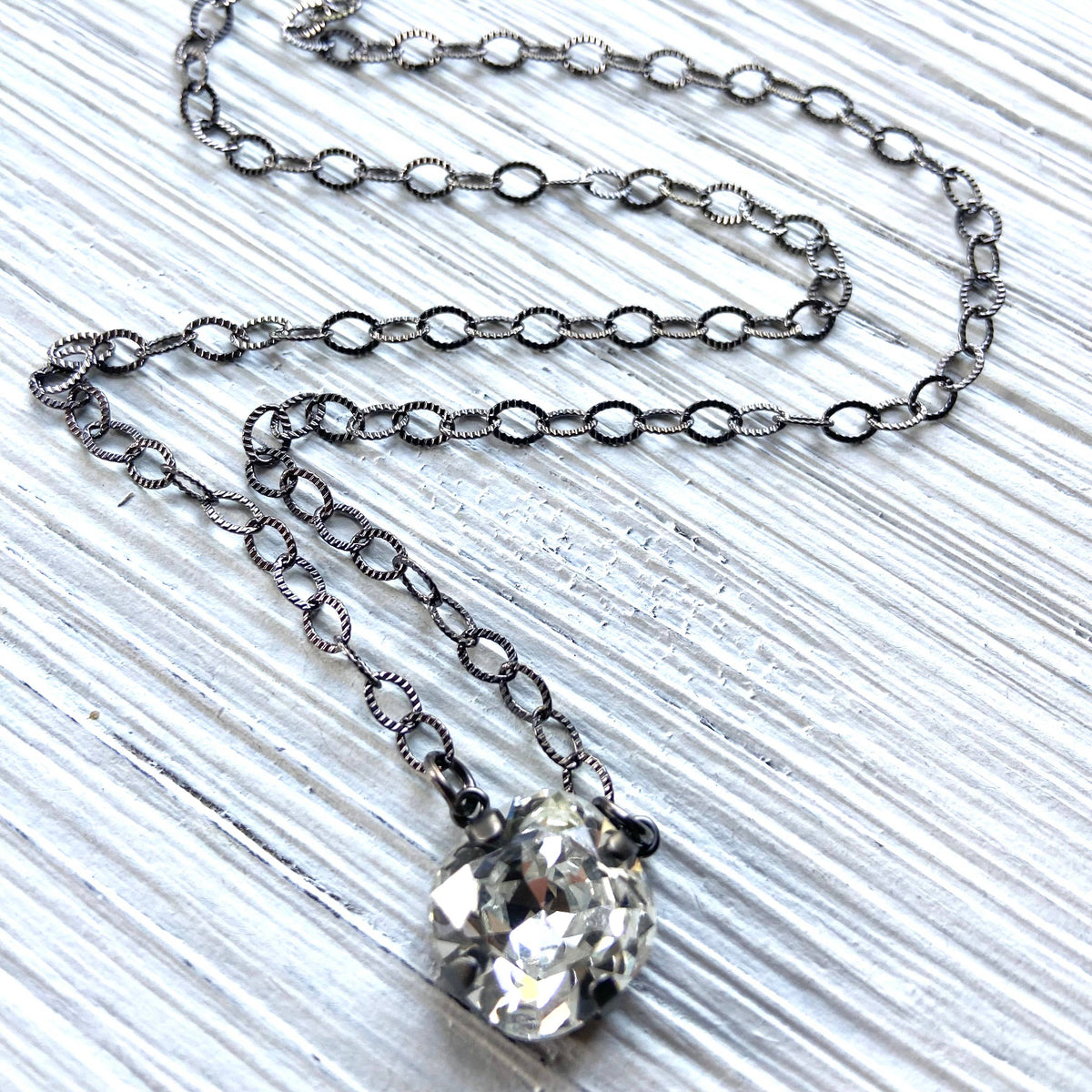 Necklace with a large crystal pendant on a textured white surface