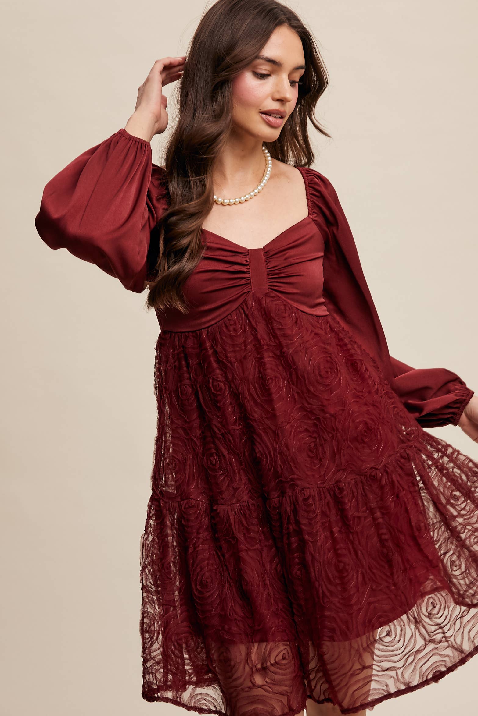 Model wearing oxblood red rosette mini dress with ruched sweetheart neckline, puff long sleeves, and tiered lace skirt — elegant and romantic look.
